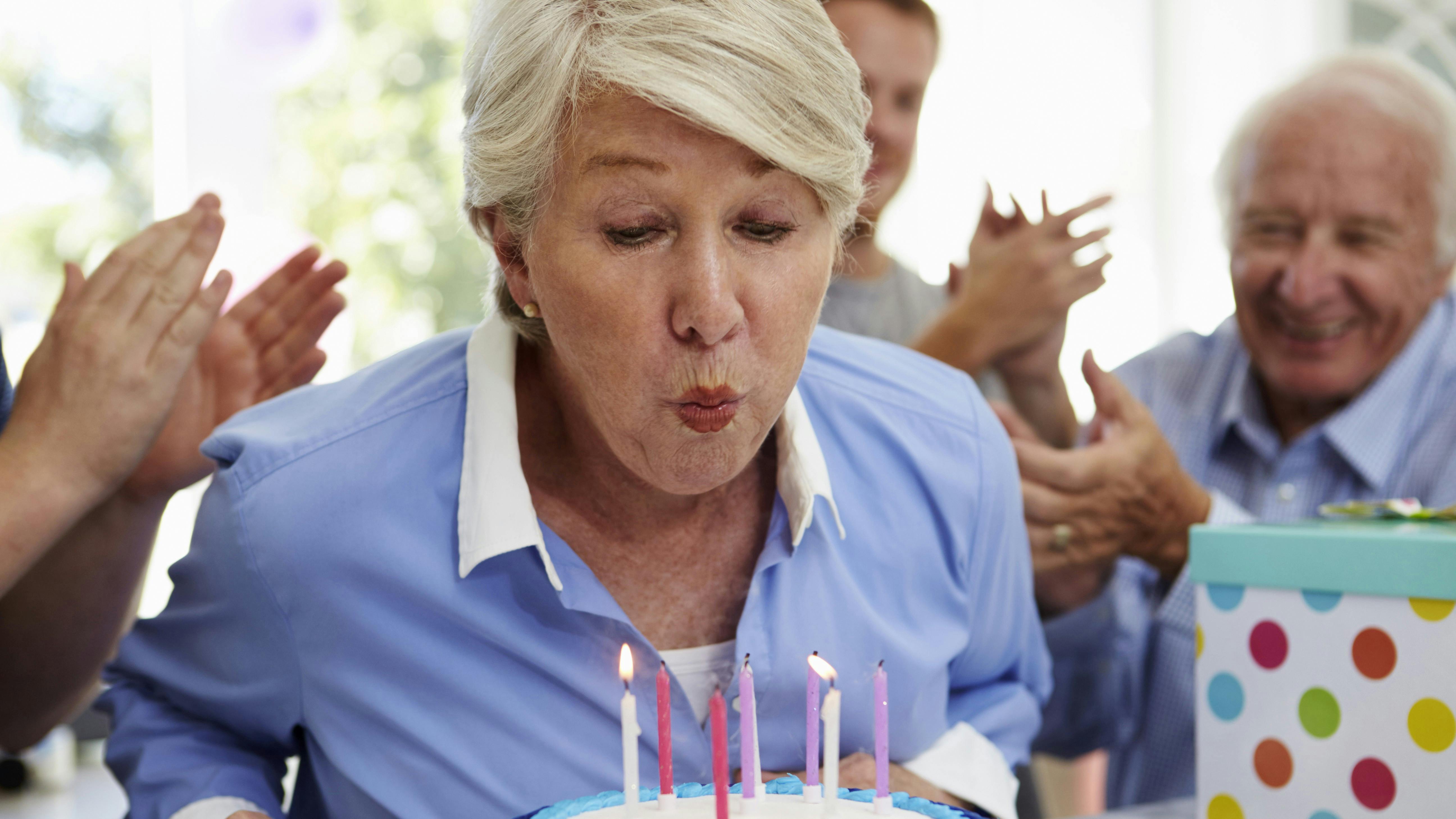 Kvinde der puster lys ud på en fødselsdagskage
