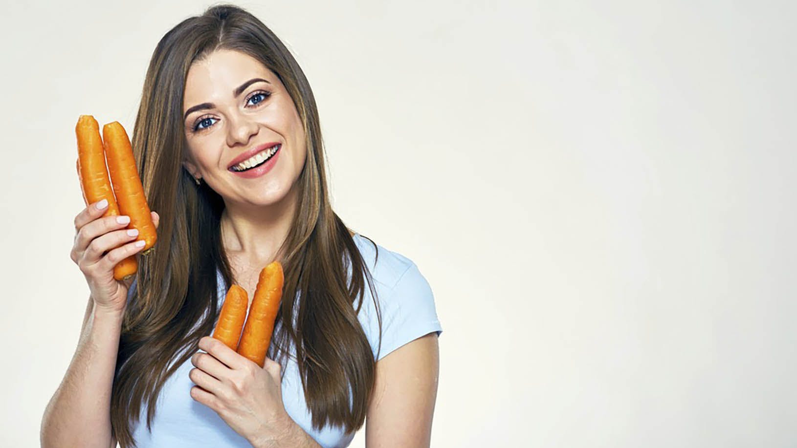 Kvinde der holder et par gulerødder