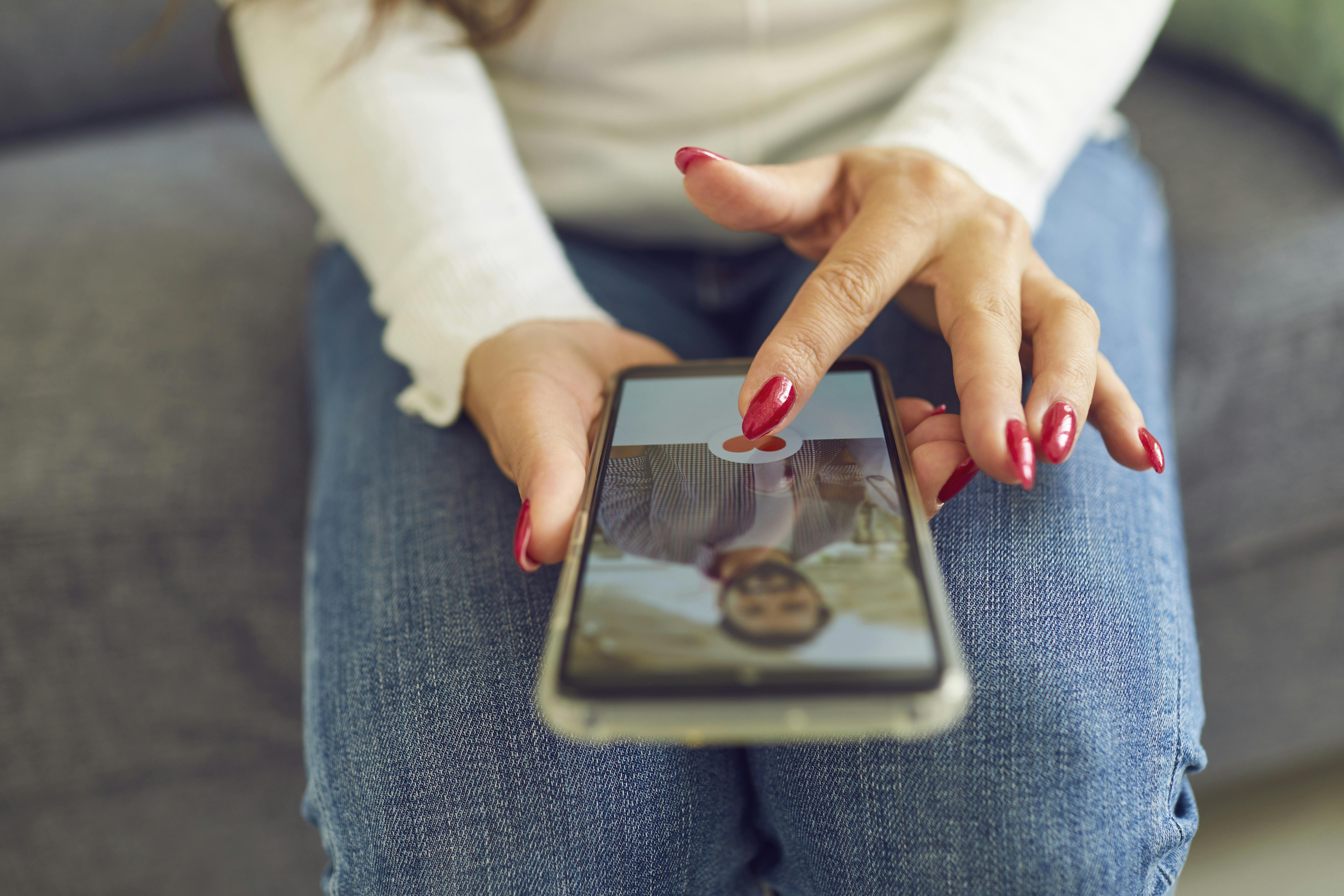 En kvinde sidder med sin mobil, der viser et foto af en mand