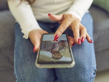 En kvinde sidder med sin mobil, der viser et foto af en mand