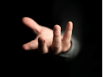 En hånd rækker ud fra en helt mørk baggrund