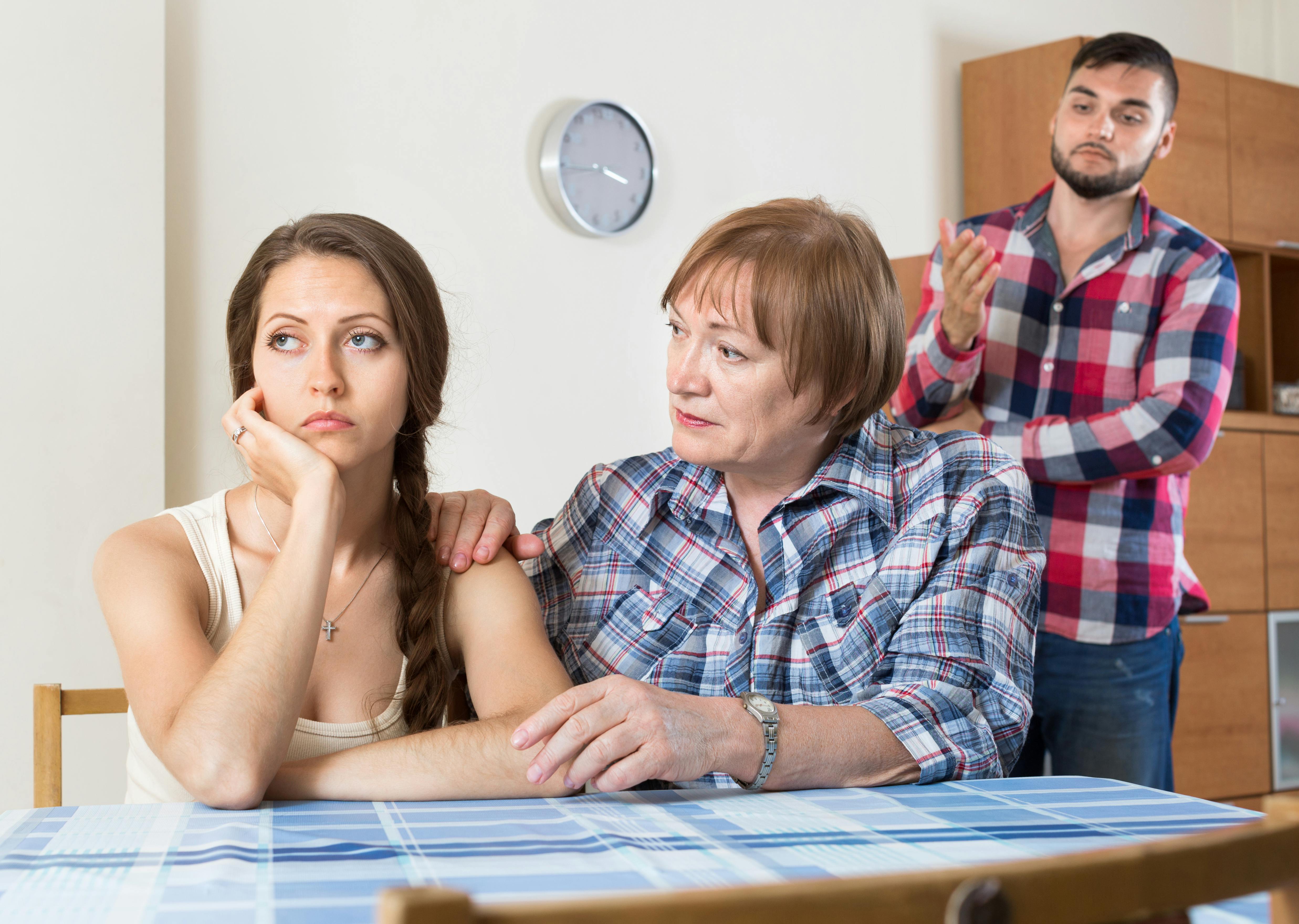 Ældre kvinde ser appellerende på surt udseende ung kvinde, mens en ung mand ser til i baggrunden 