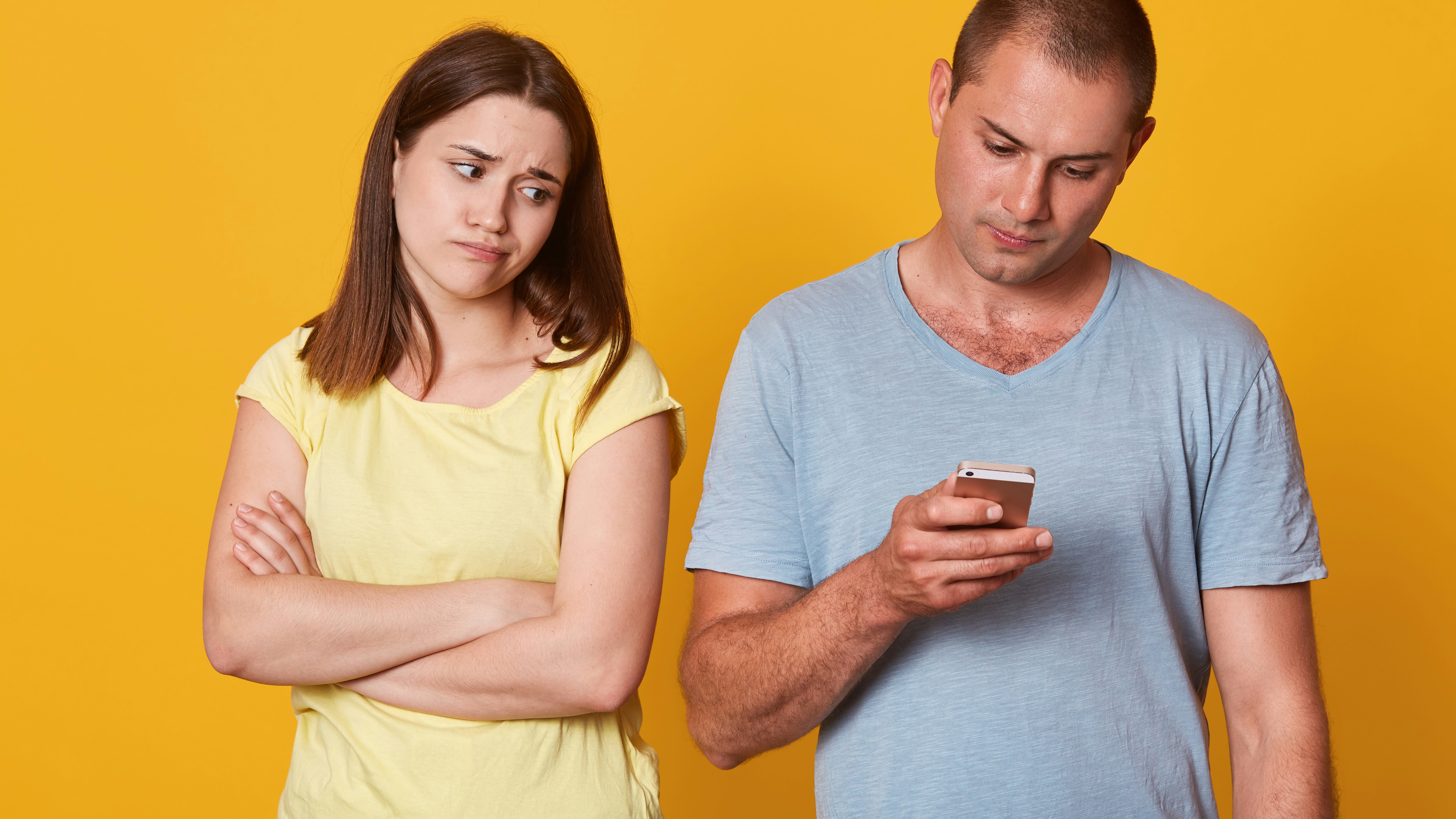 Ung kvinde ser surt på sin kæreste, der er opslugt af sin mobil.