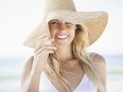Kvinde iført strandhat står på en strand