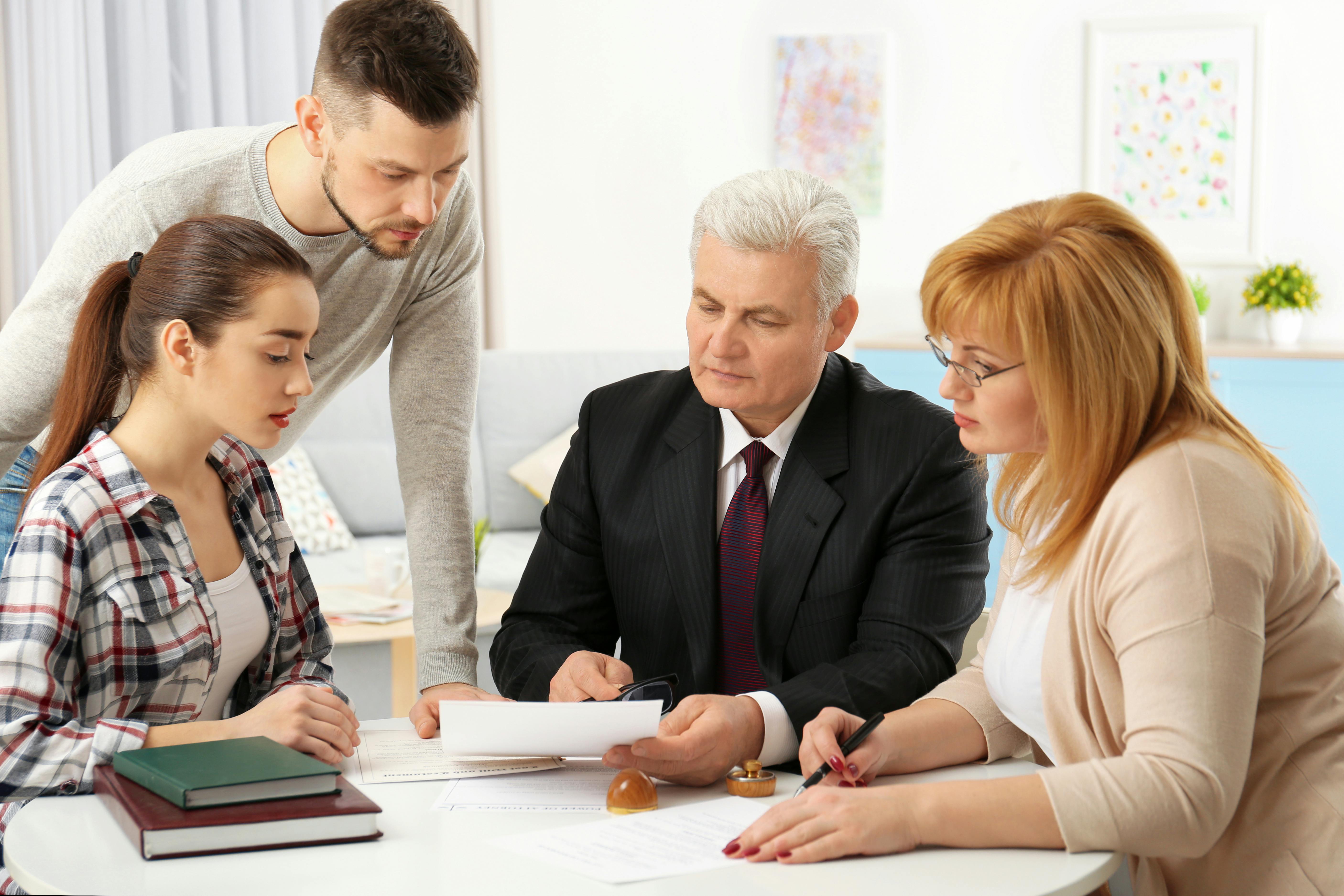 Flere generationer af en familie sidder rundt om et bord og ser på papirer