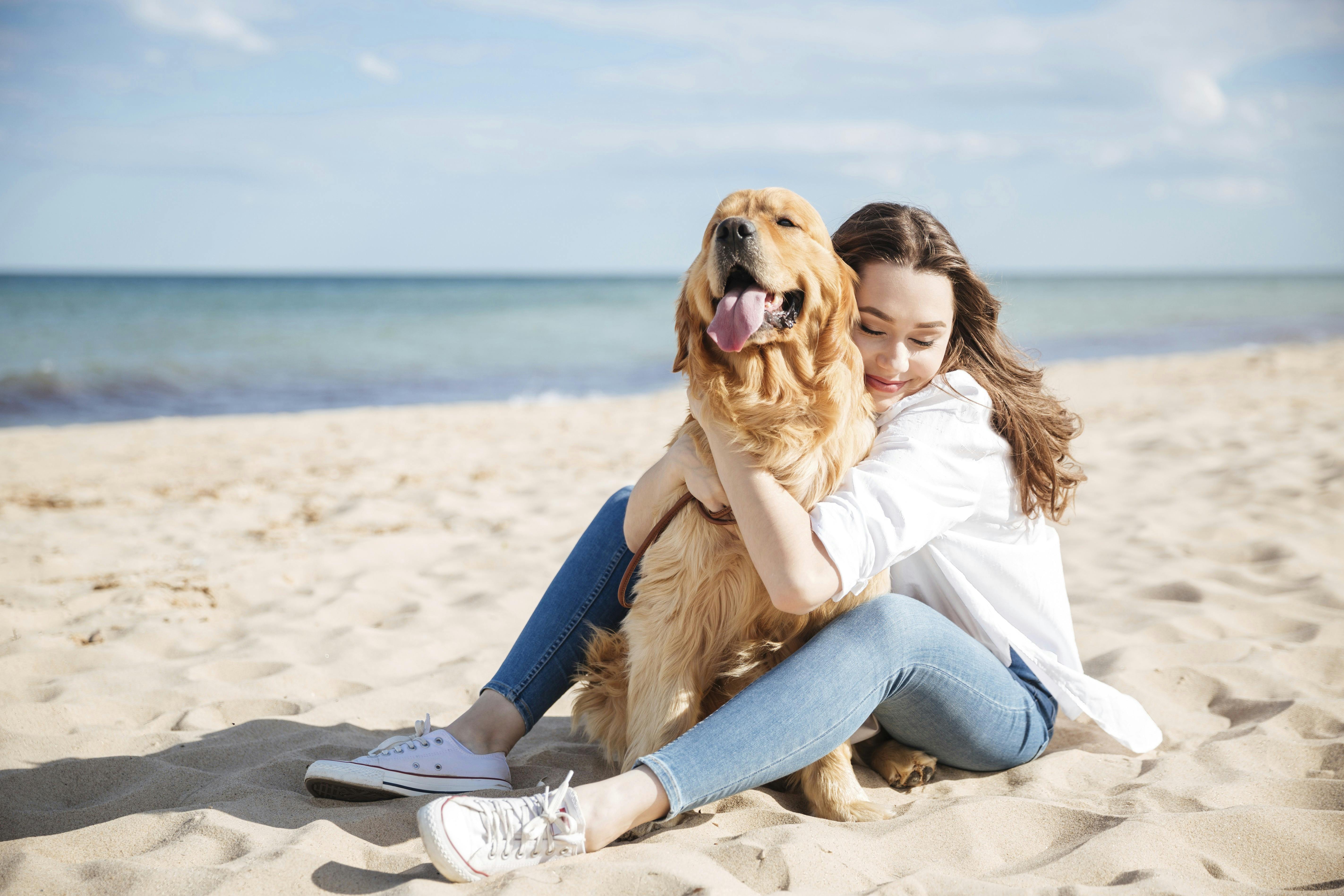 Kvinde og hund sidder på en strand