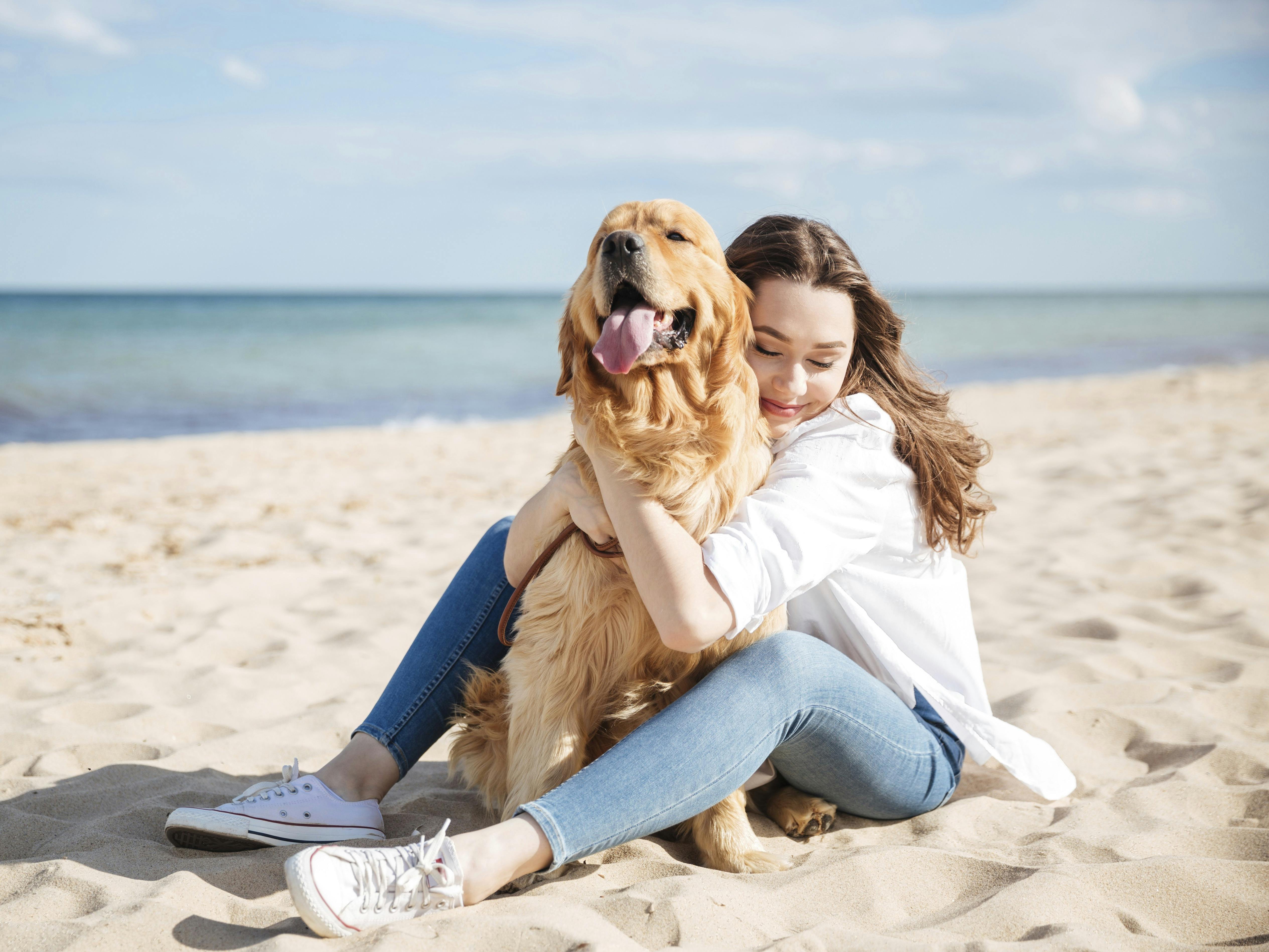 Kvinde og hund sidder på en strand