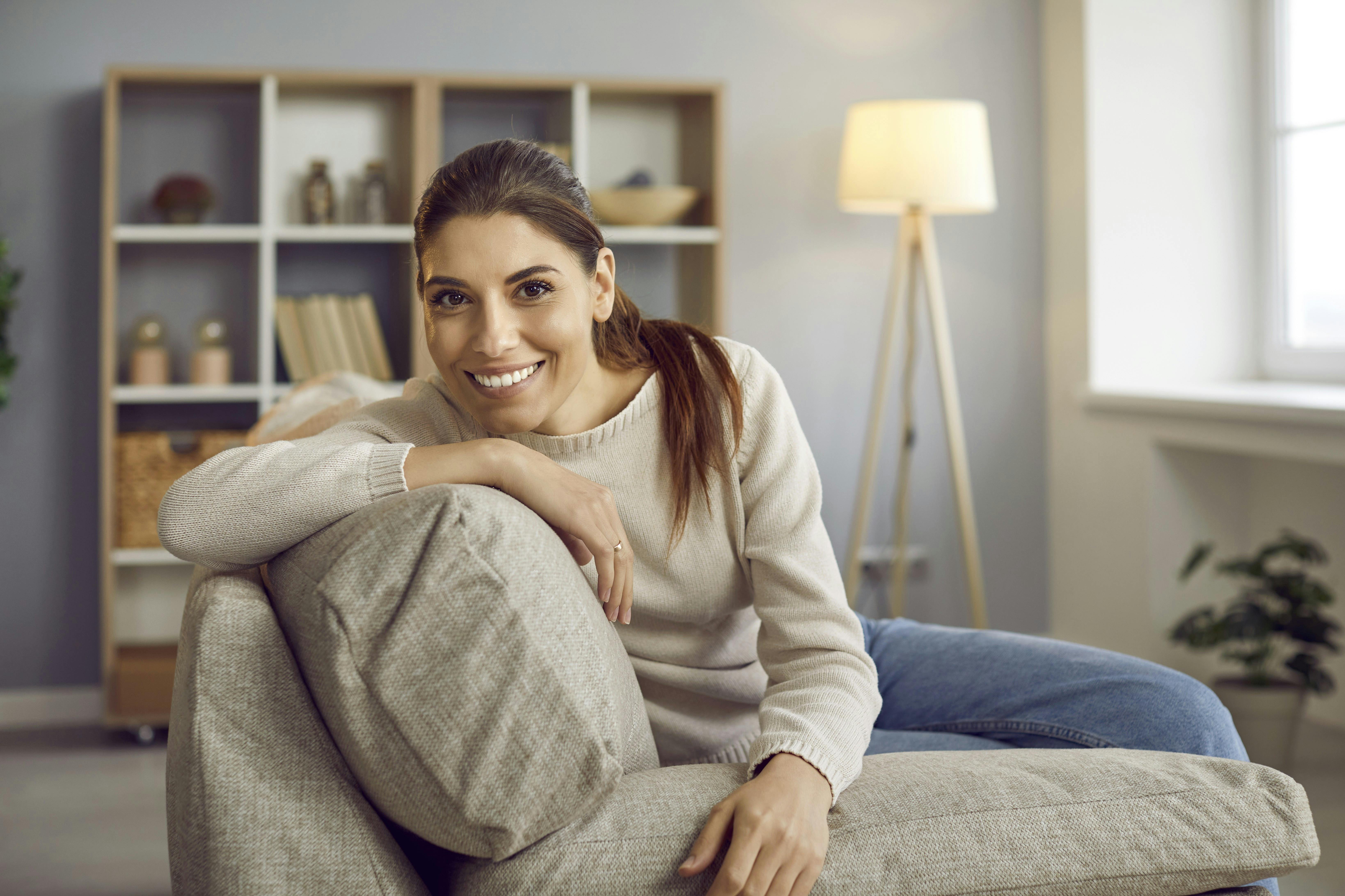 Smilende kvinde sidder i en sofa