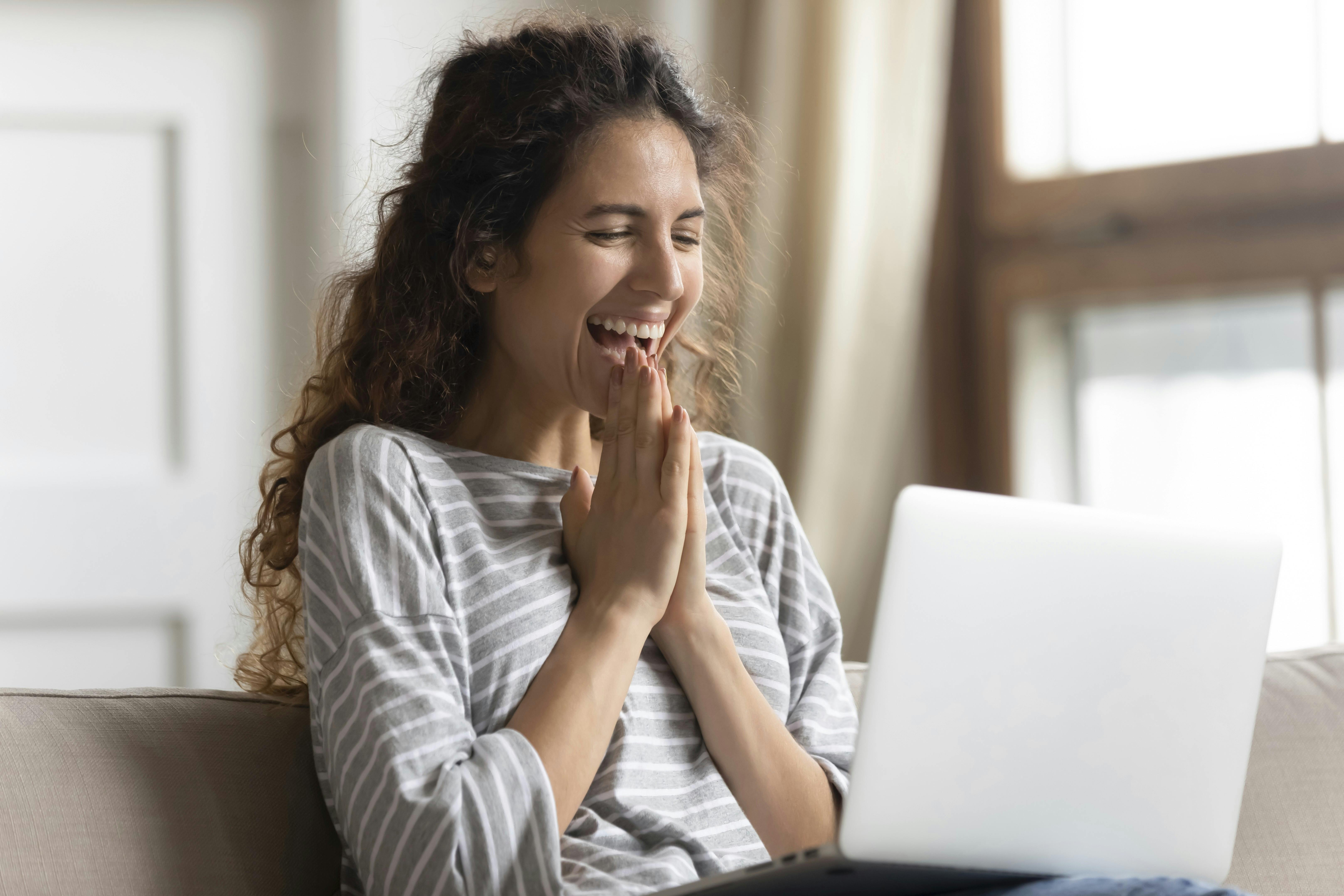 Begejstret kvinde kigger på sin computer