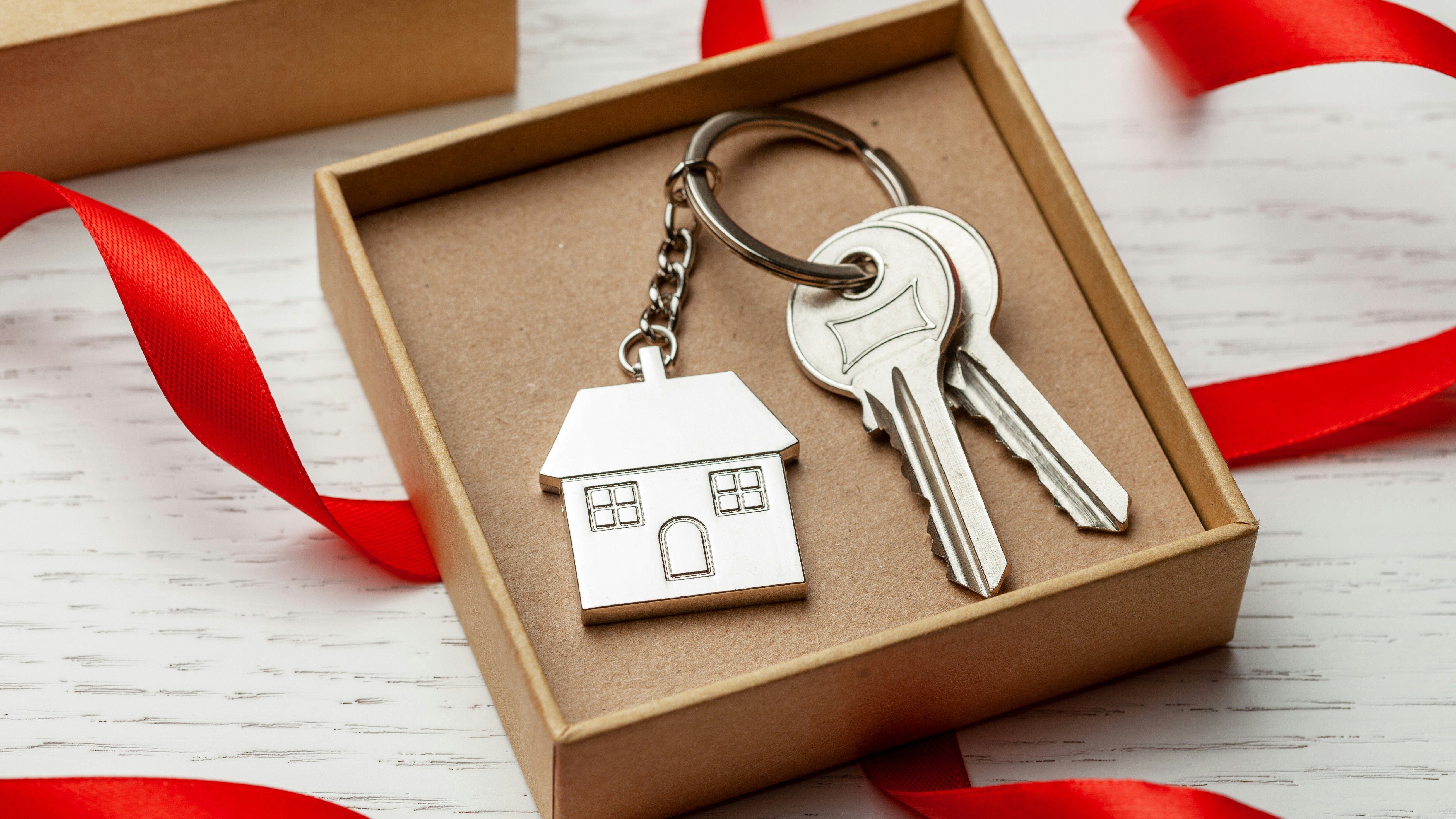 Lille gaveæske med et sæt nøgler samt en nøglering med et hus.
