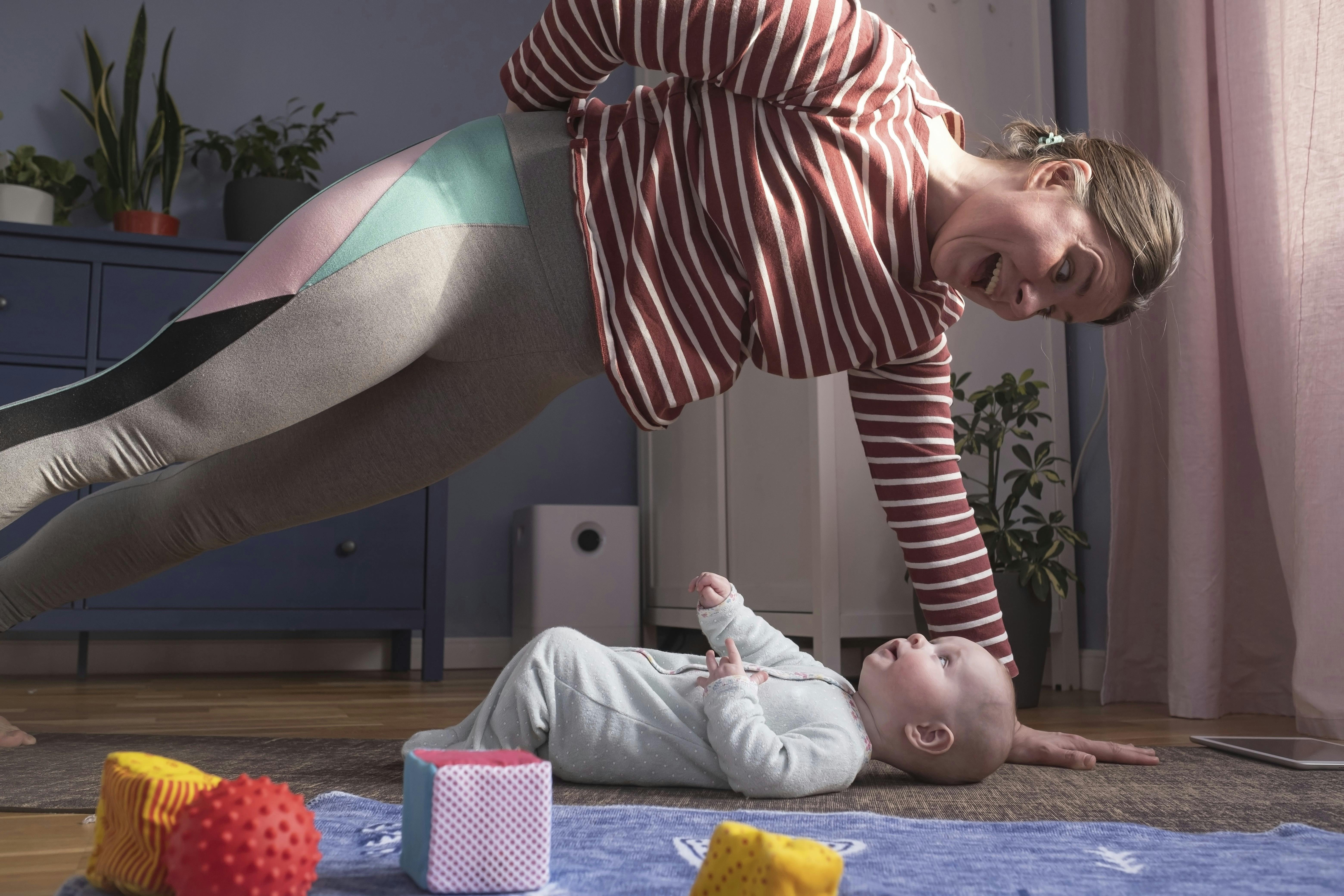 Kvinde dyrker motion, mens baby ligger på gulvet