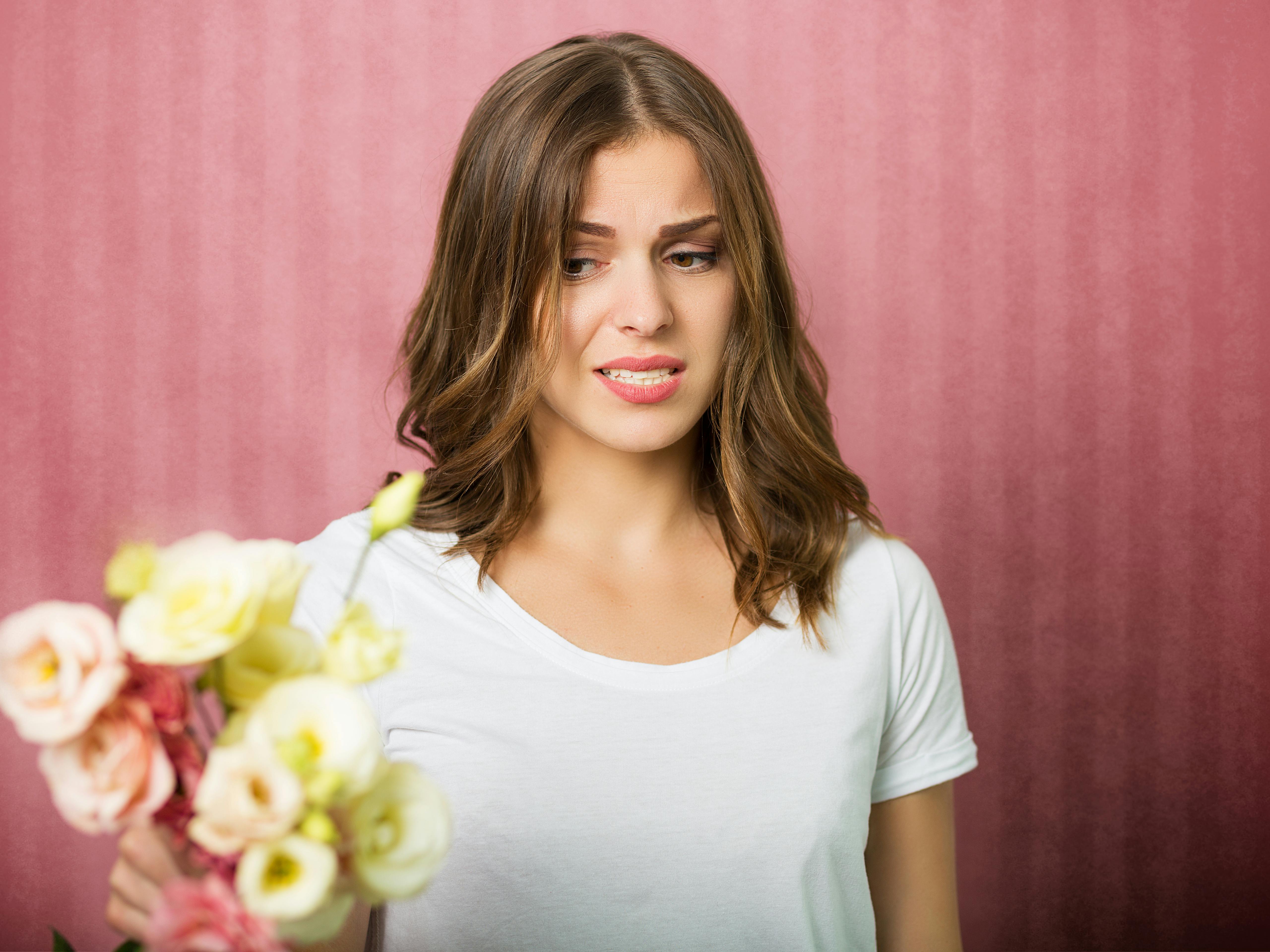 Ung kvinde ser skeptisk på en smuk buket blomster.