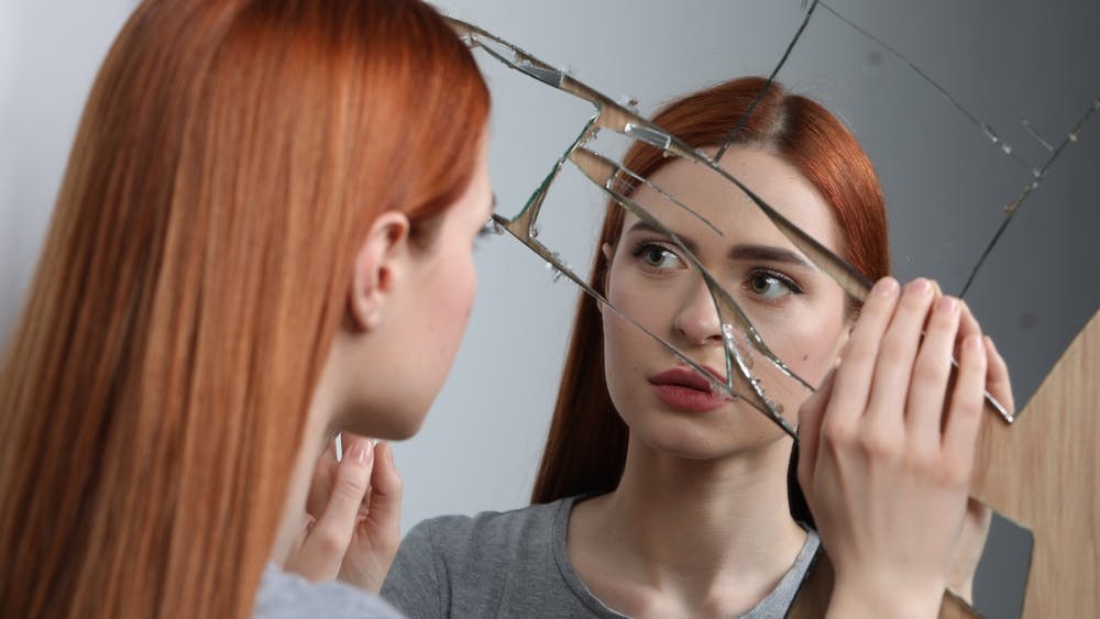 Ung kvinde spejler sig i et knust spejl.