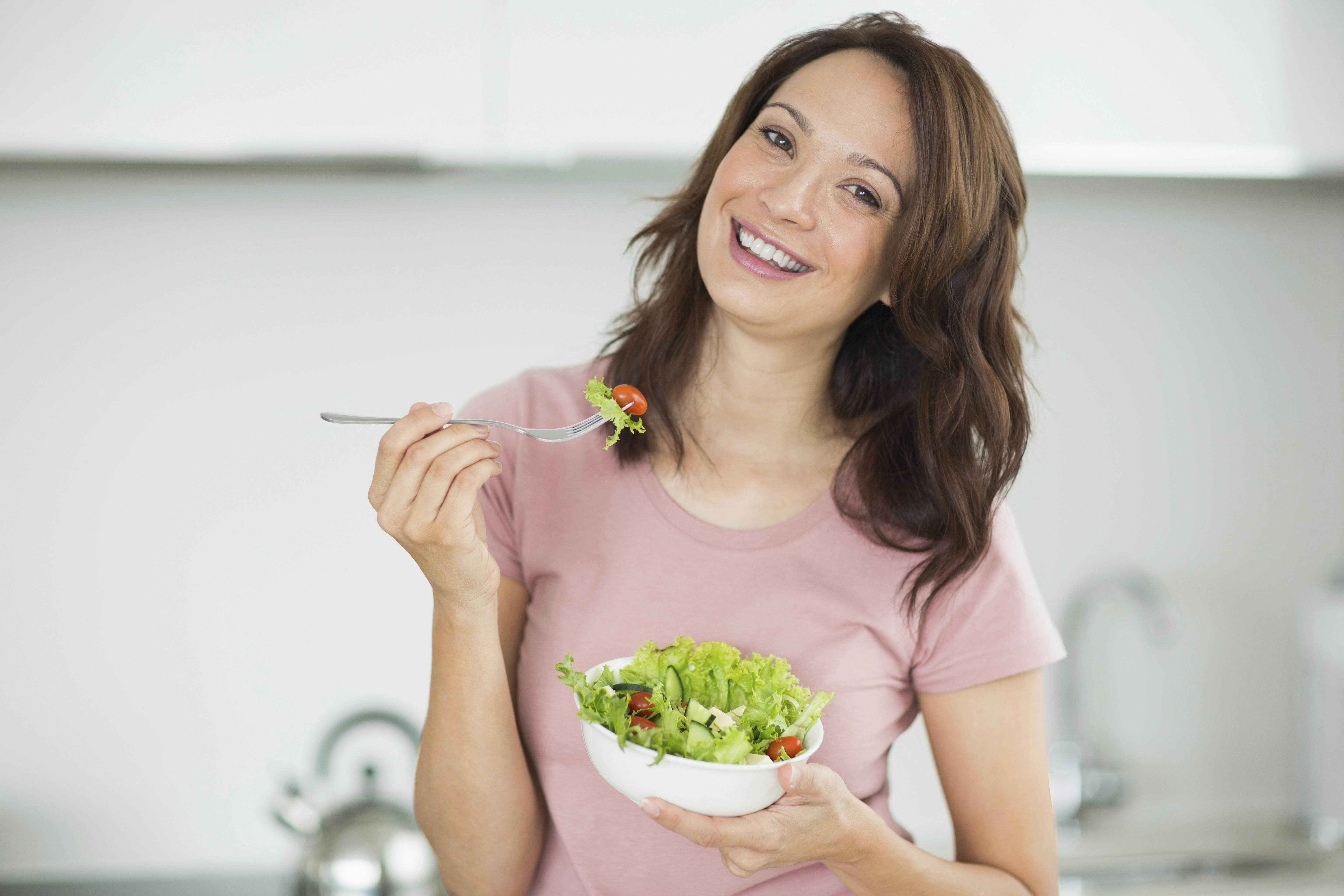 Glad kvinde, der spiser en salat