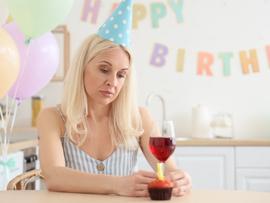 Midaldrende kvinde ser trist på en fødselsdagskage