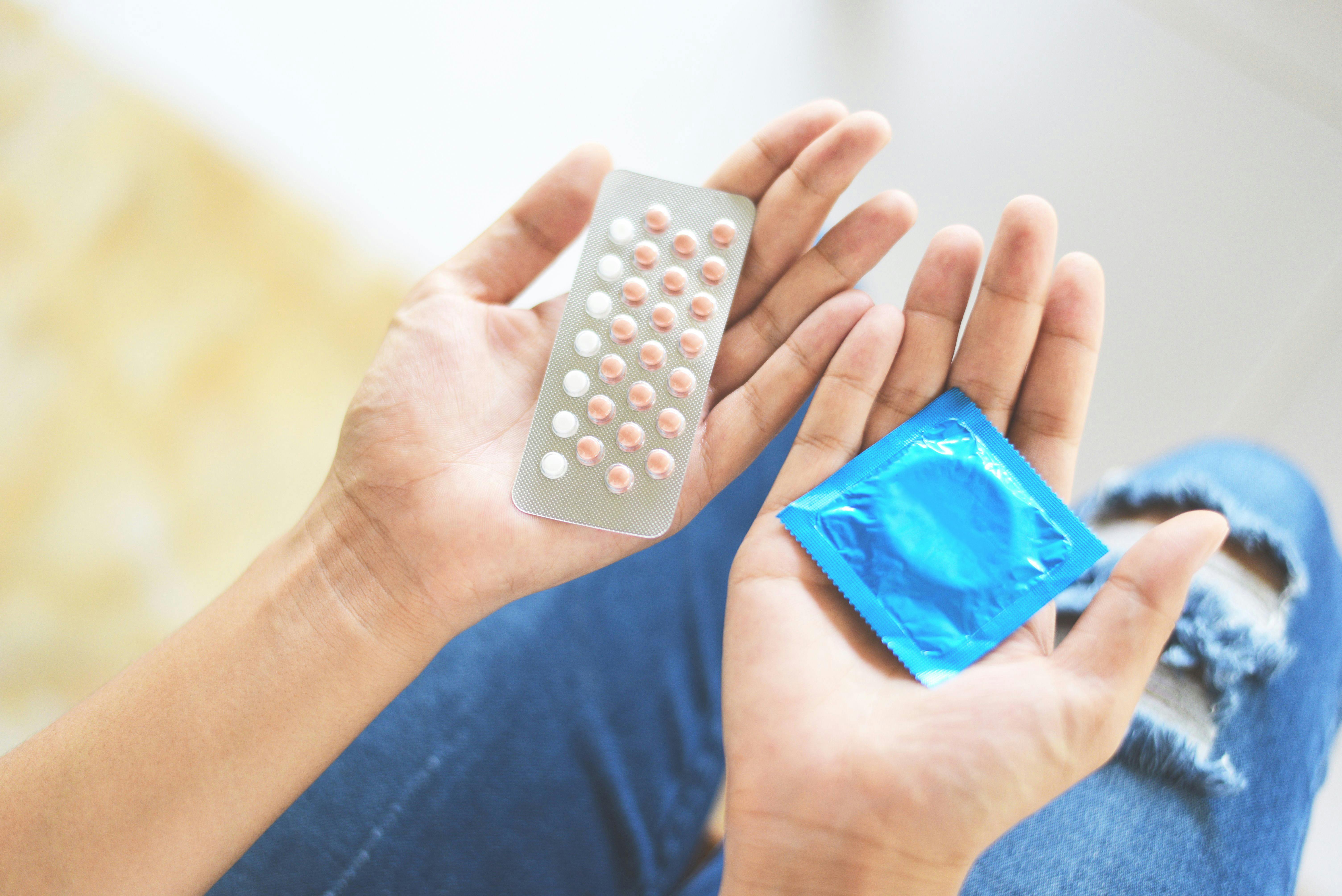 Kvinde, der holder p-piller og et kondom
