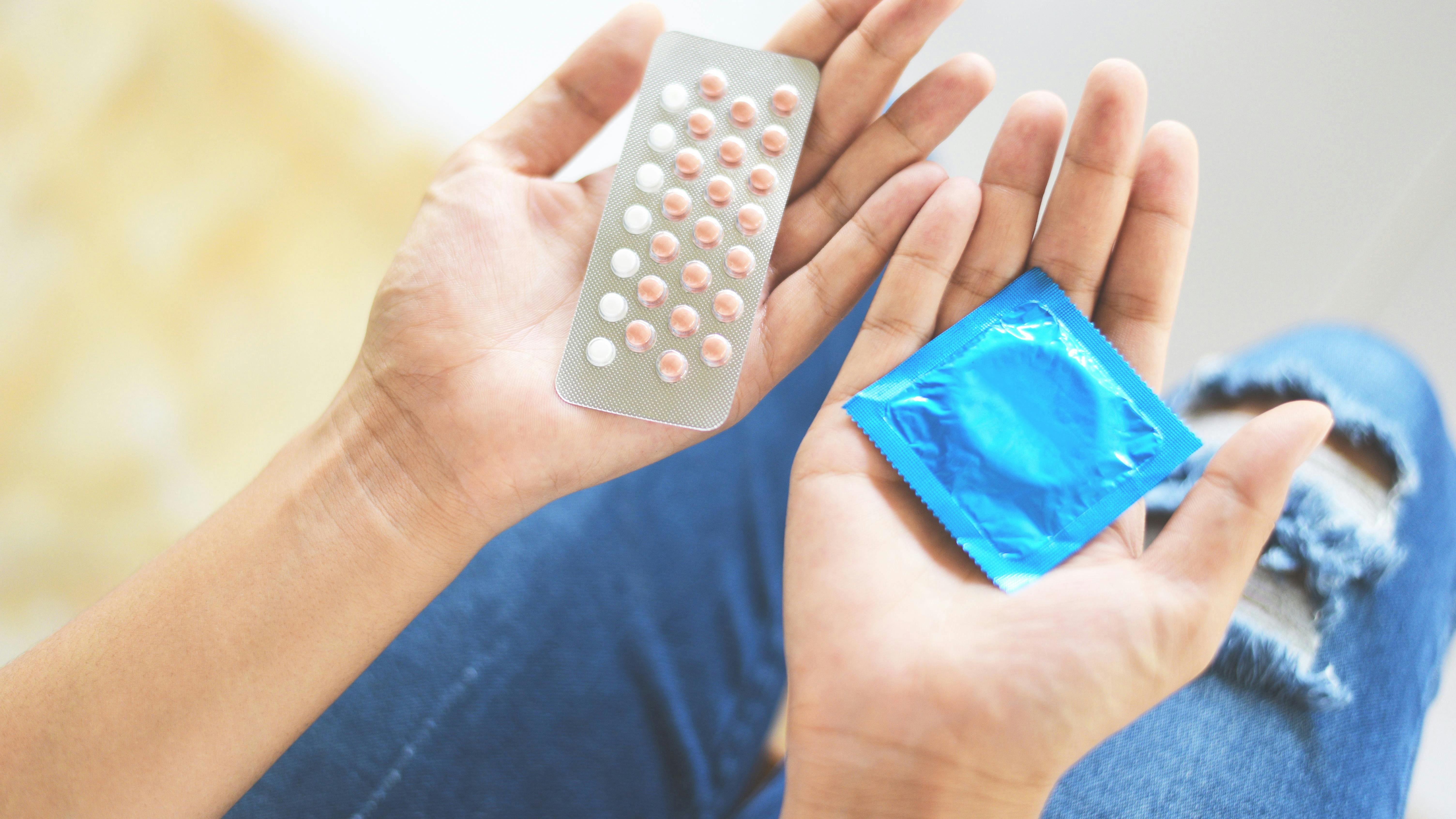 Kvinde, der holder p-piller og et kondom