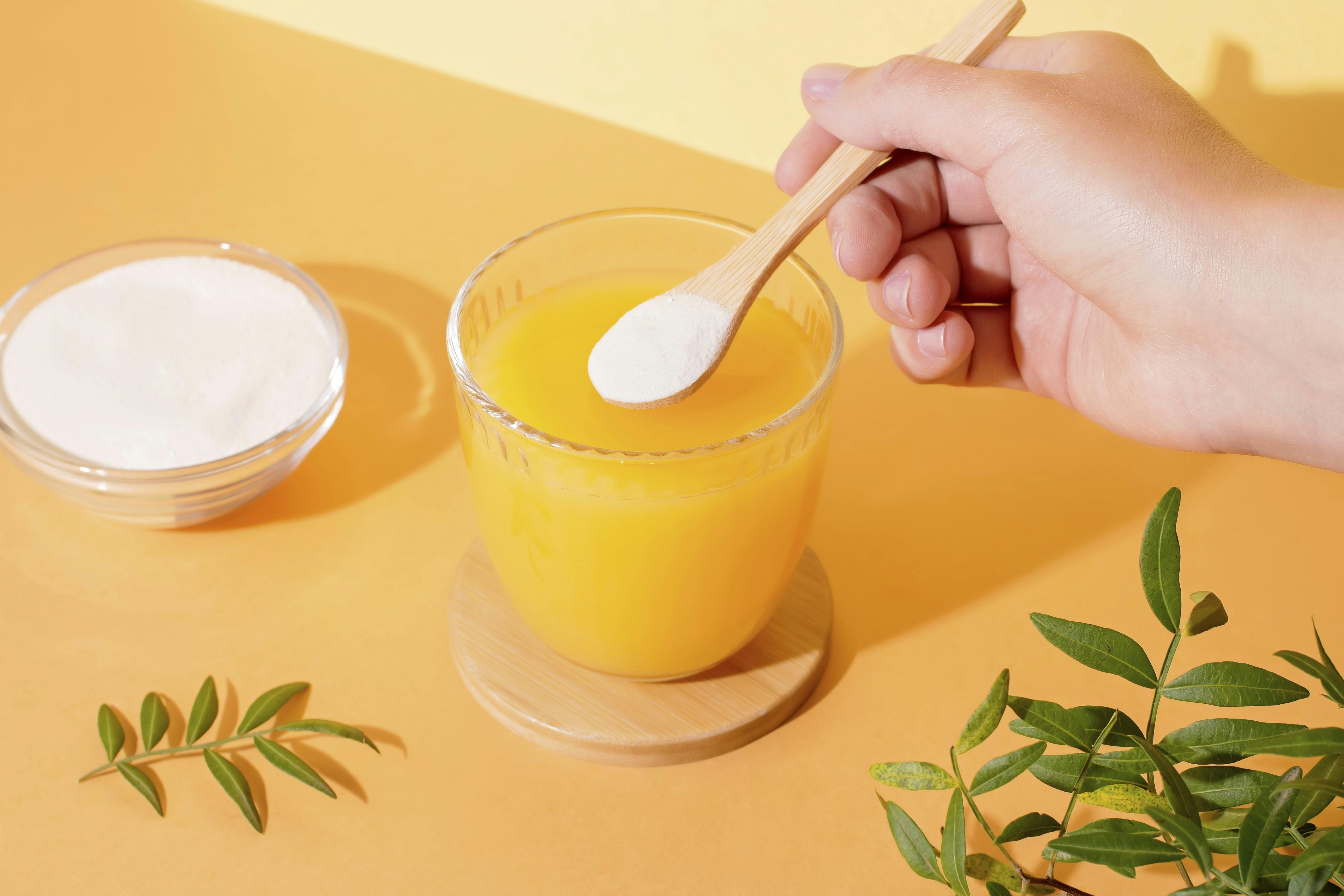 Kvinde tilføjer collagen til sin appelsinjuice