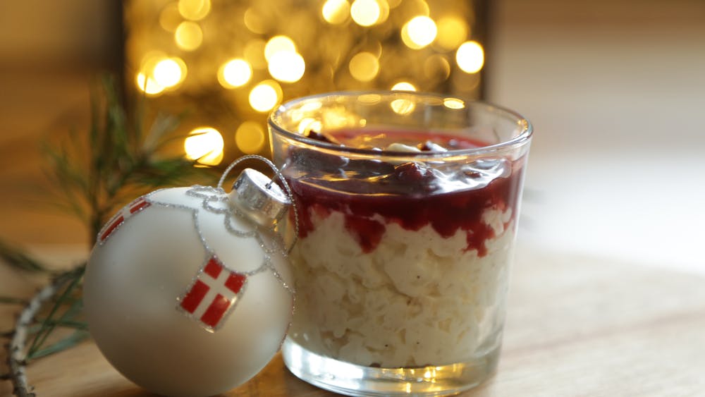 Glas med en portion risalamande med en julekugle ved siden af.
