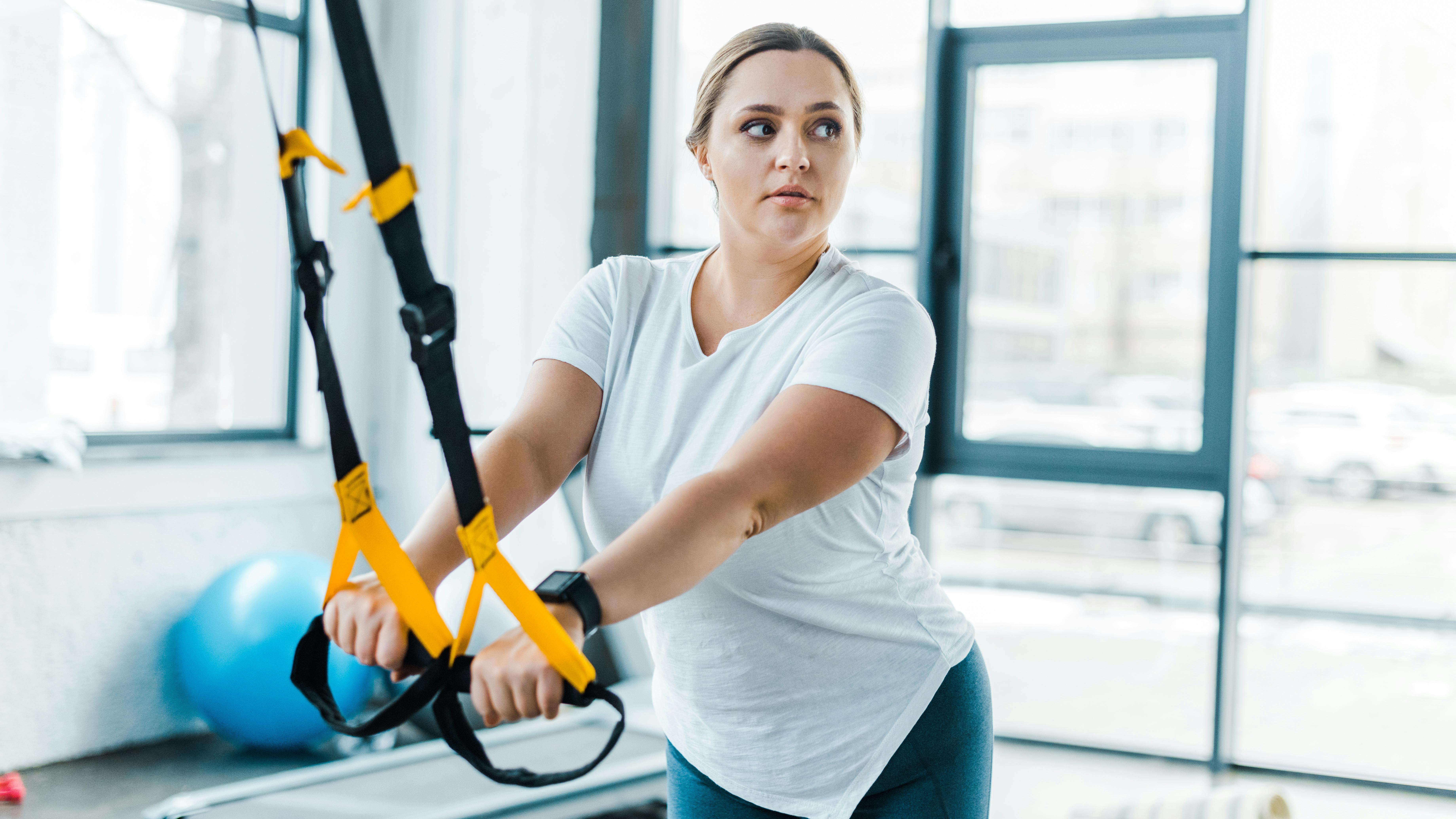 Ung kvinde træner sine arme i fitnesscenter