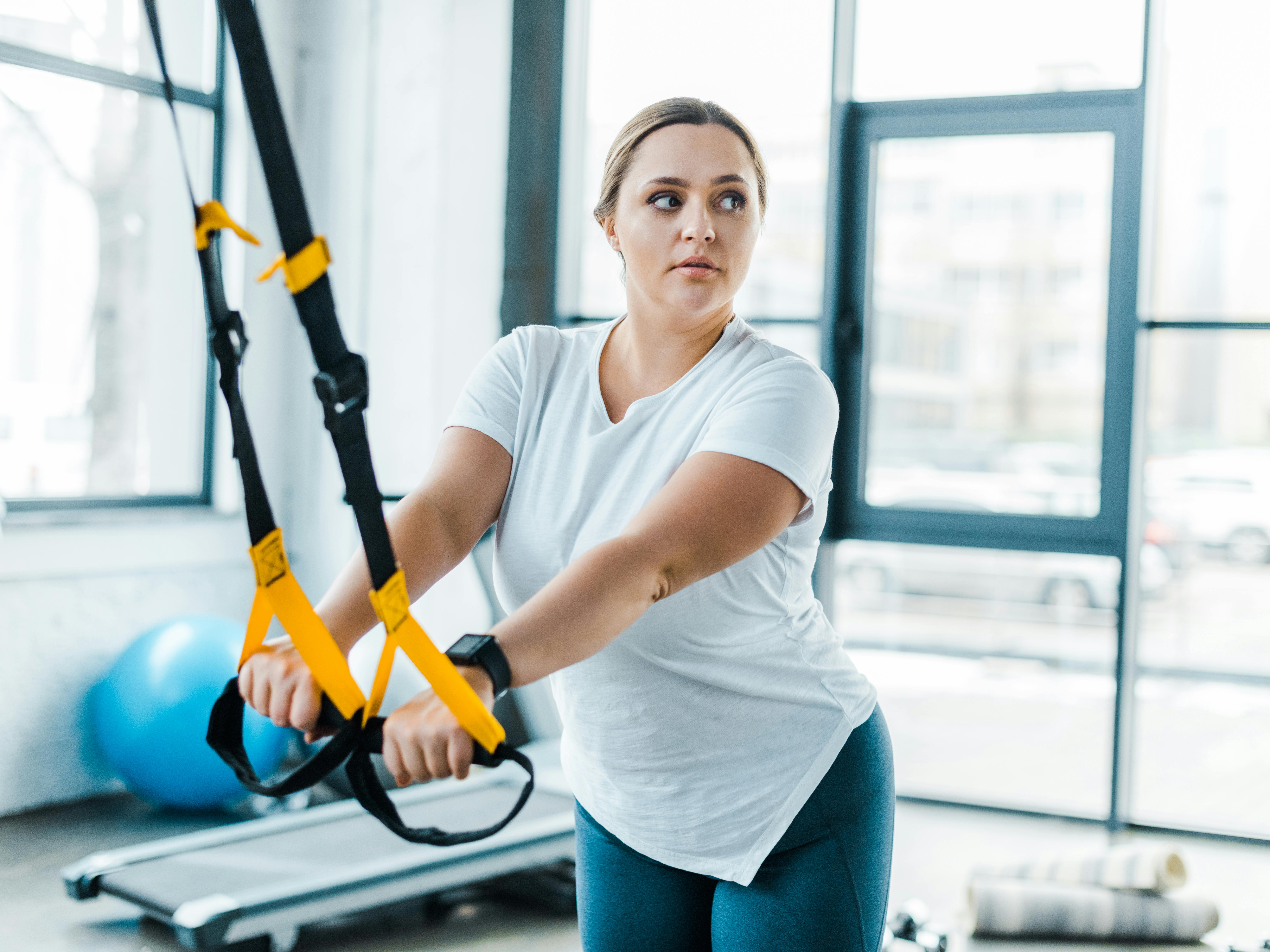 Ung kvinde træner sine arme i fitnesscenter
