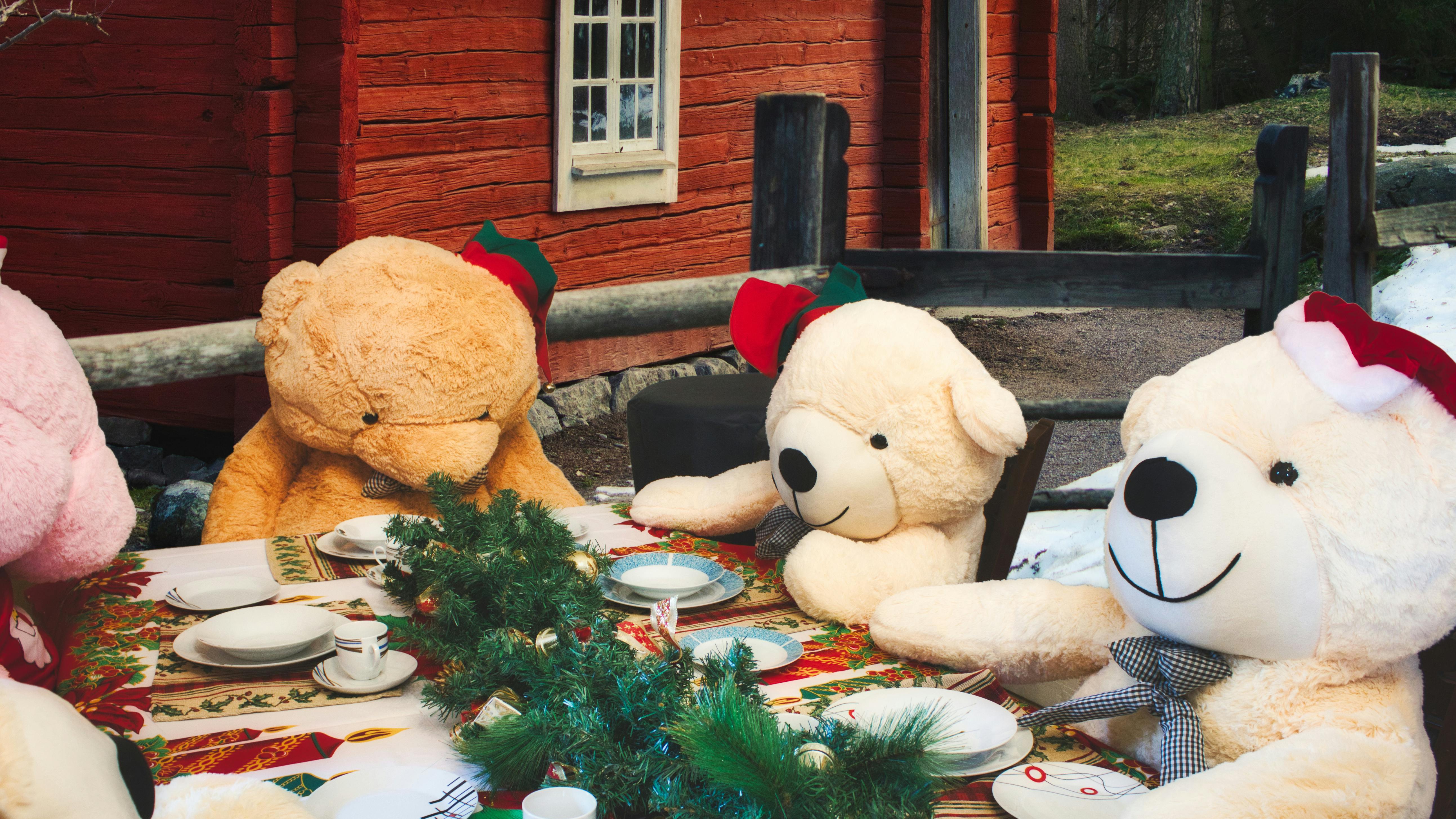 Fire bamser sidder omkring et flot dækket julebord