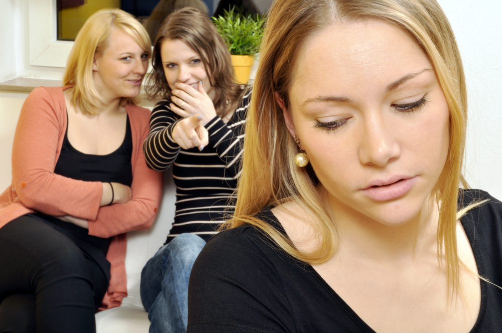 To kvinder bagtaler en tredje kvinde