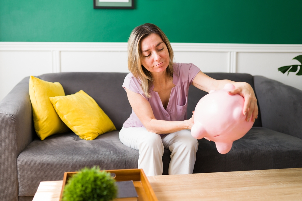 Kvinde tømmer sin sparegris ud på bordet, og der er ikke særlig mange penge i.