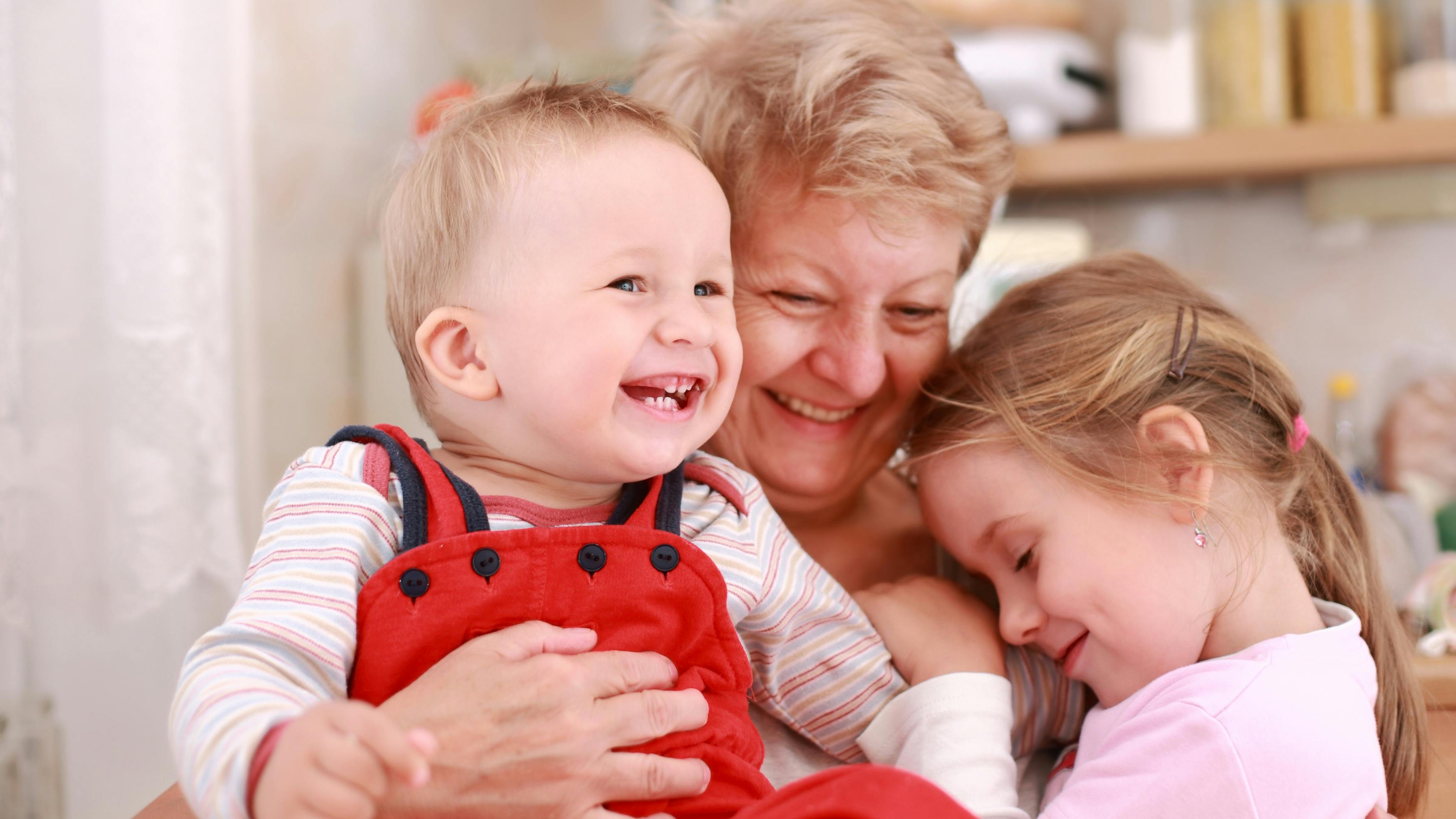 Smilende bedstemor krammer sine to børnebørn