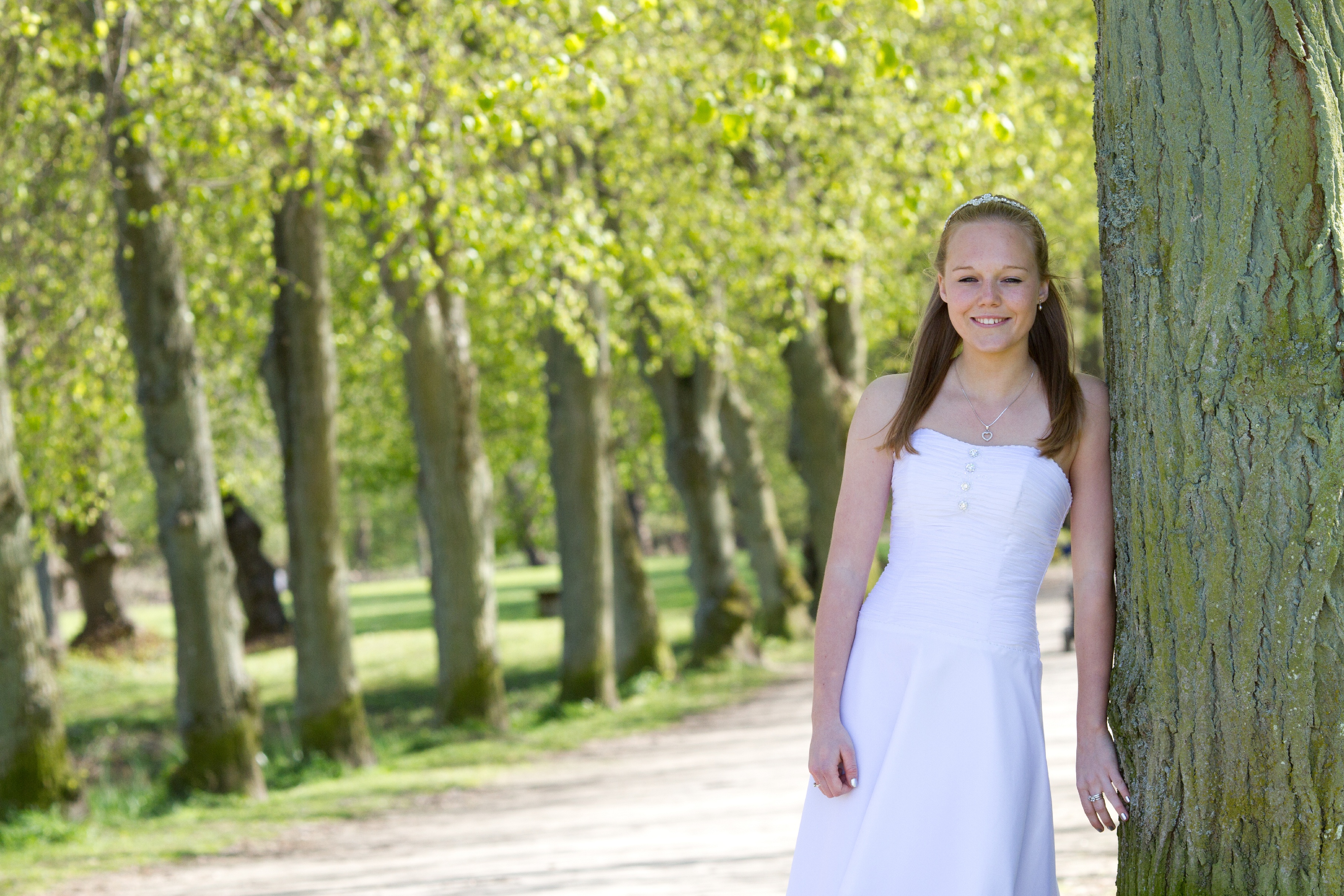 Ung glad konfirmand-pige fotograferet i park