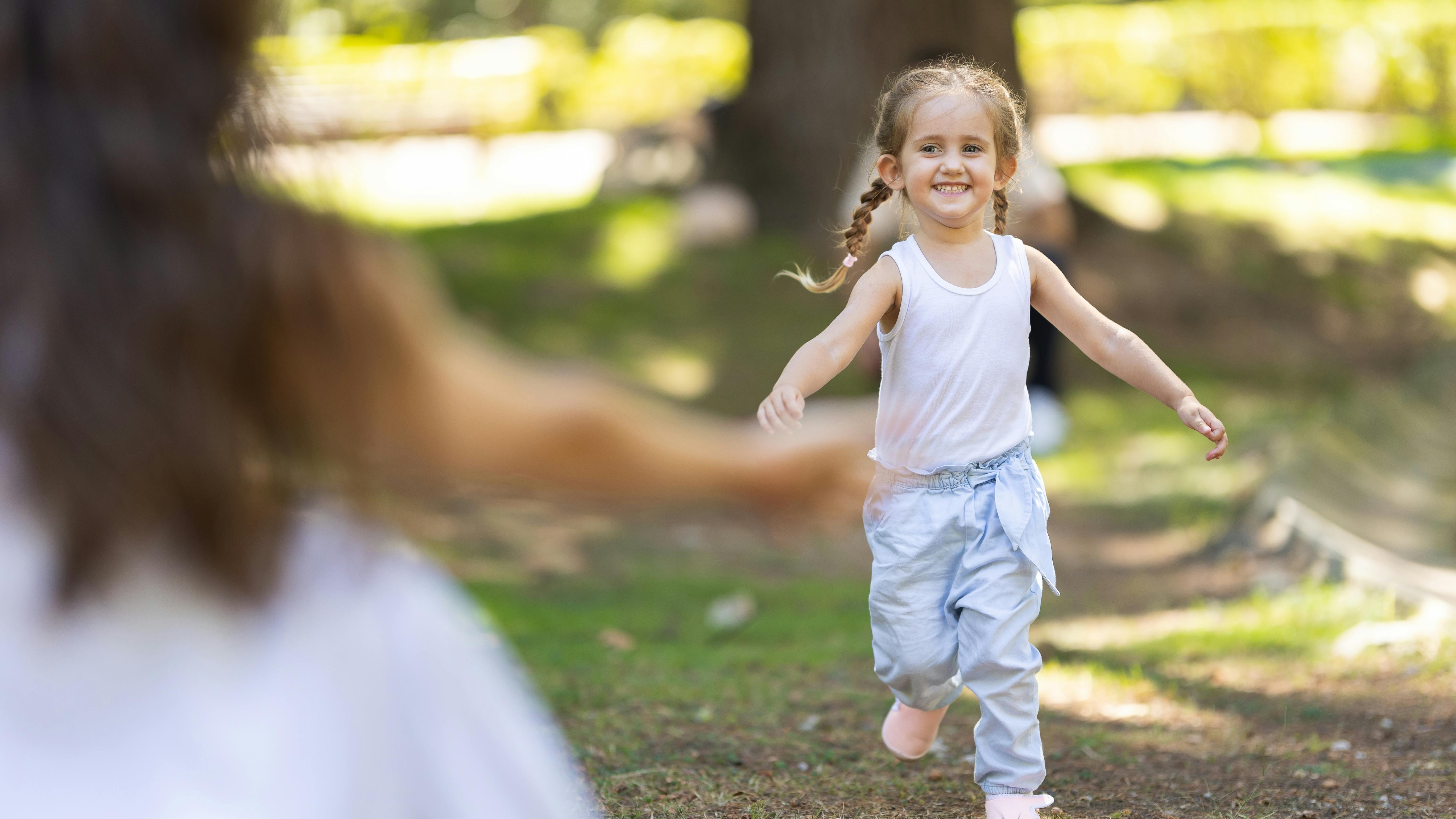 Lille pige løber med udbredte arme mod sin mor