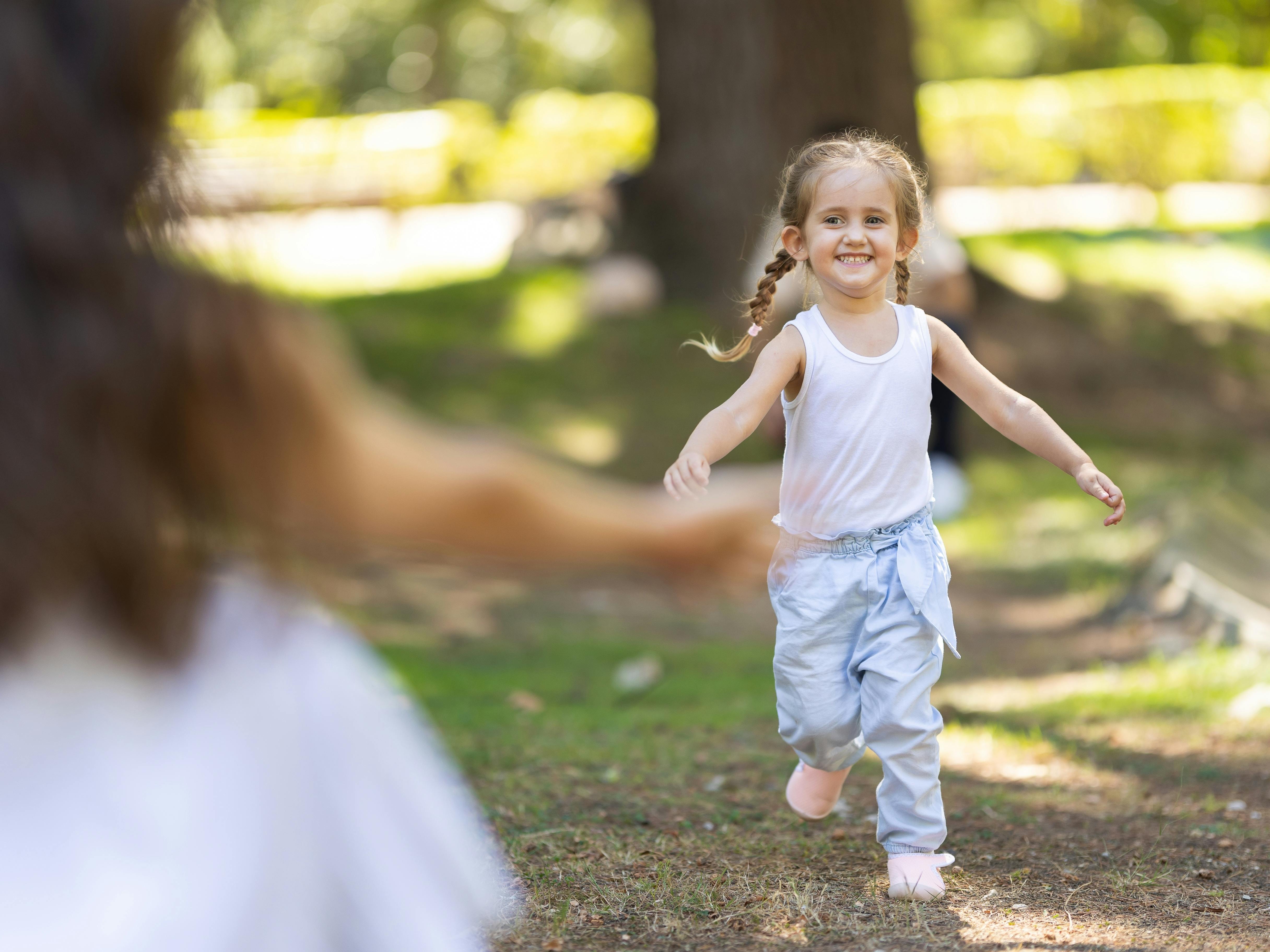 Lille pige løber med udbredte arme mod sin mor