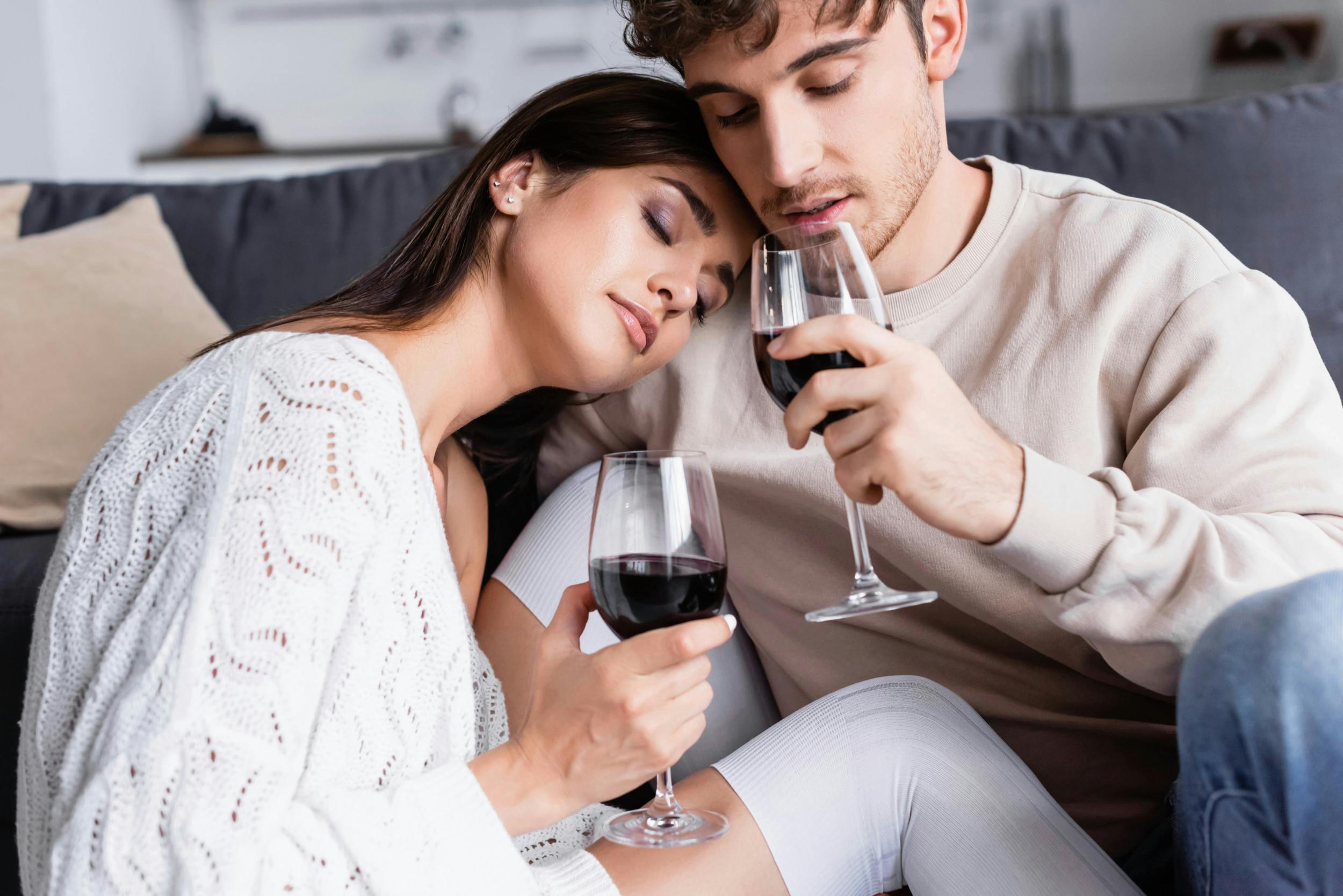 To unge sidder tæt sammen med hver sit glas vin
