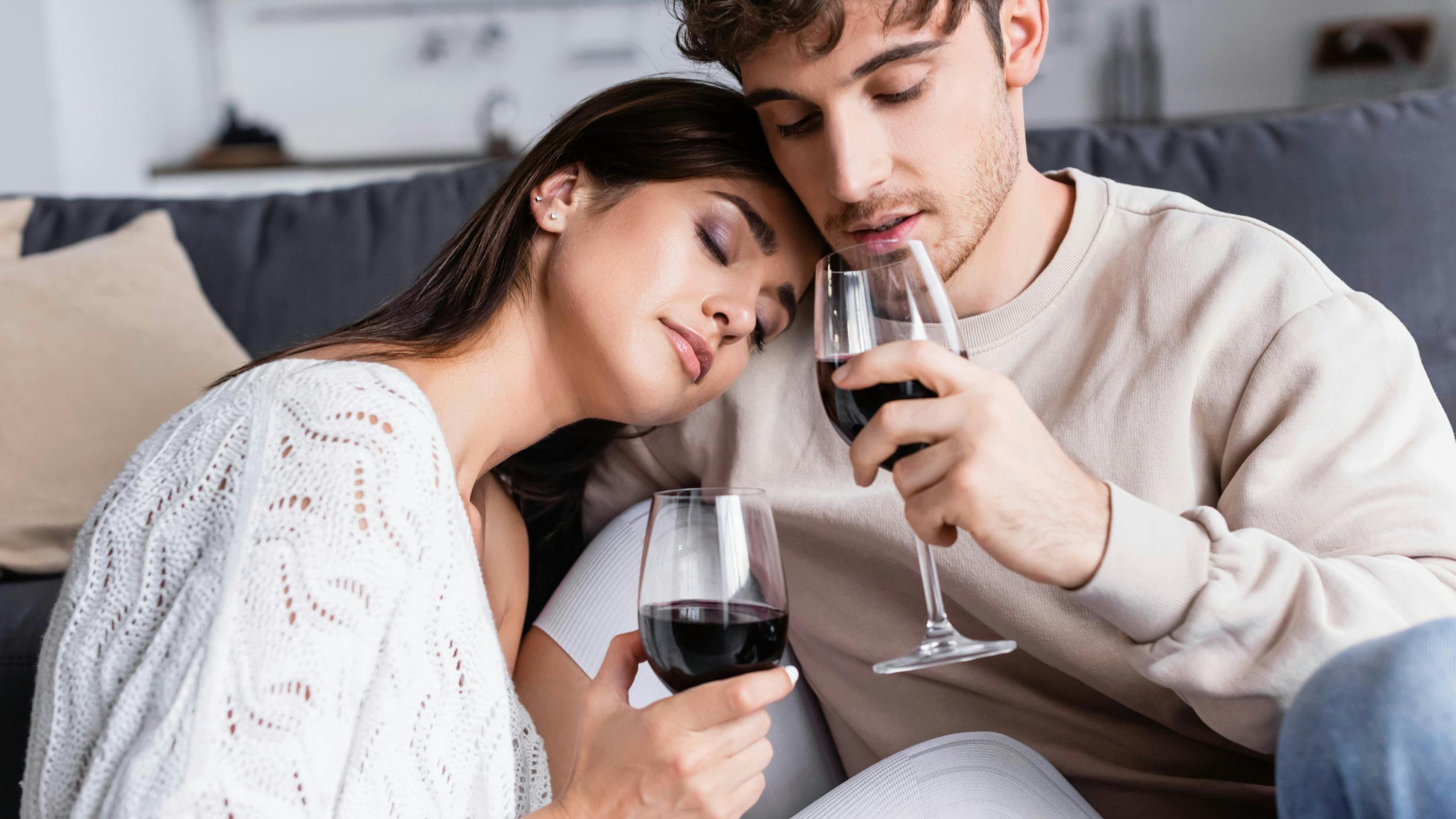 To unge sidder tæt sammen med hver sit glas vin