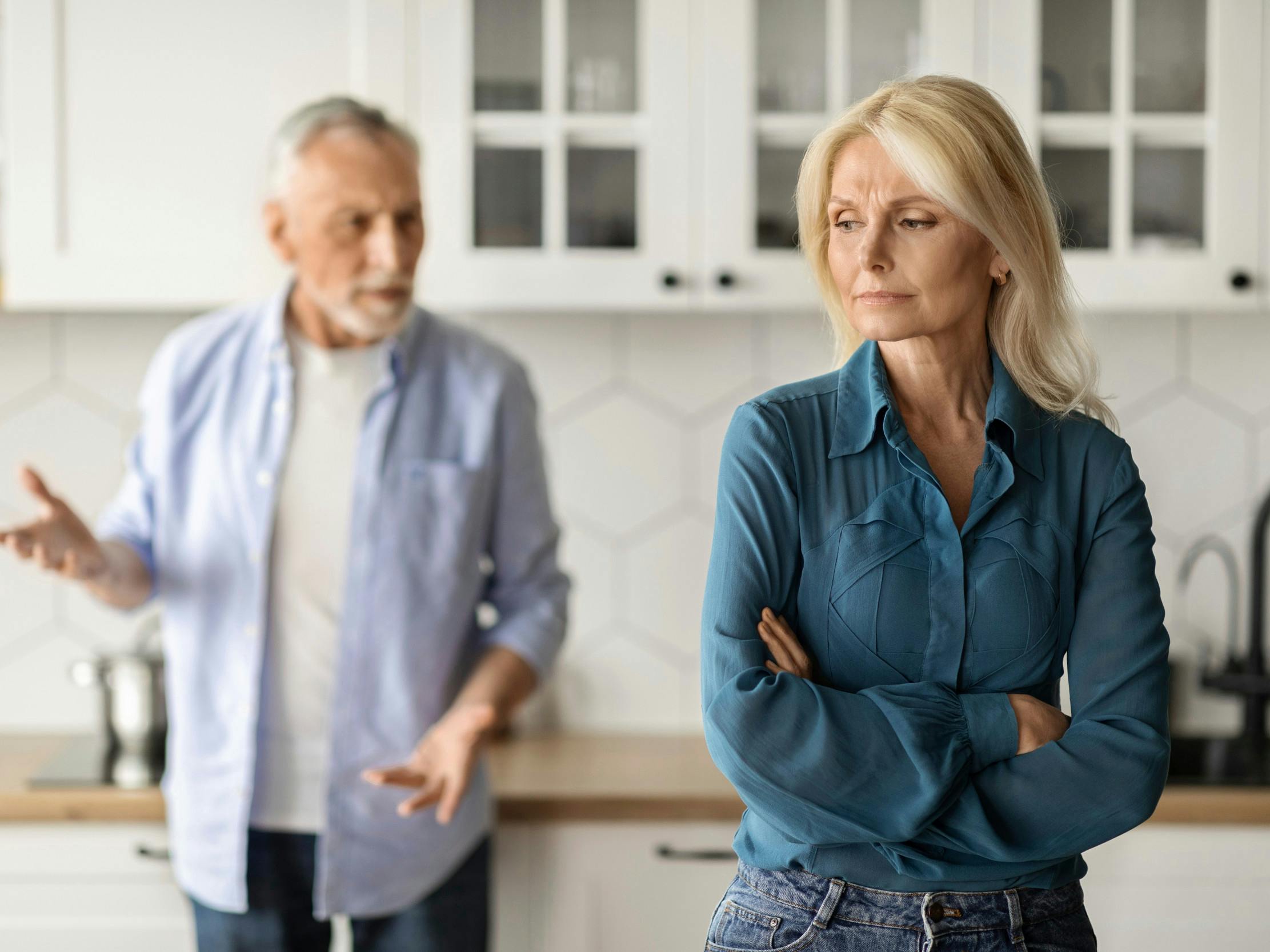 En midaldrende mand prøver at forklare sig over for sin kone, der ser vred ud.