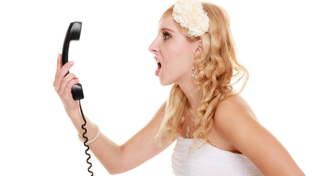 Vred brud råber ind i et telefonrør.
