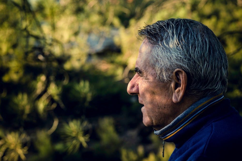 Ældre mand ser ind mod skyggefulde grønne buske