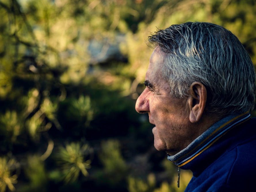 Ældre mand ser mod skyggefulde grønne buske