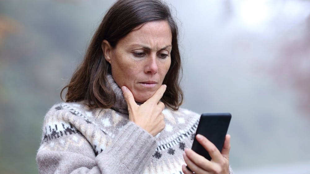 Midaldrende kvinde ser på sin mobil.