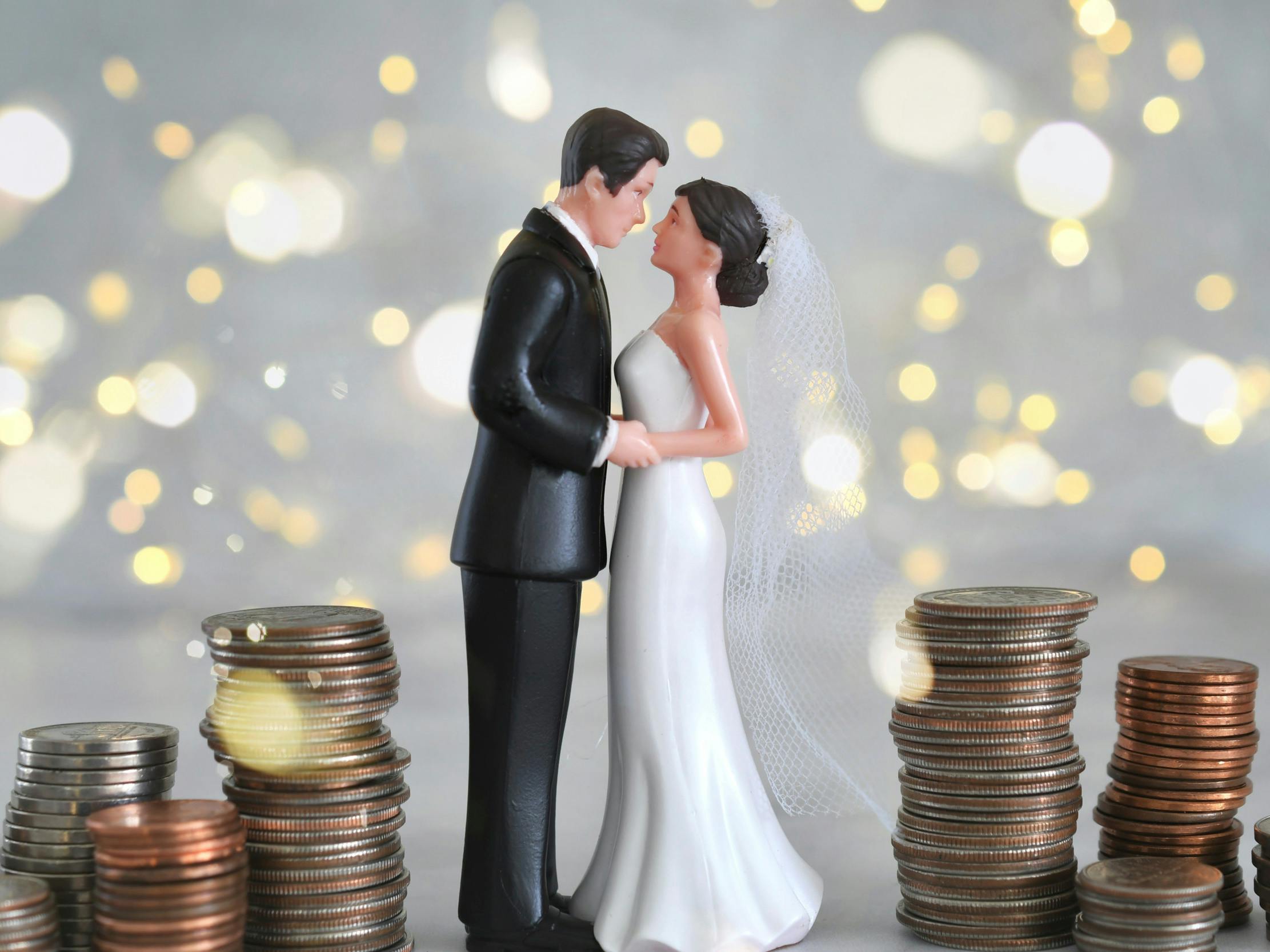 Figur af brudepar står mellem stakke af mønter