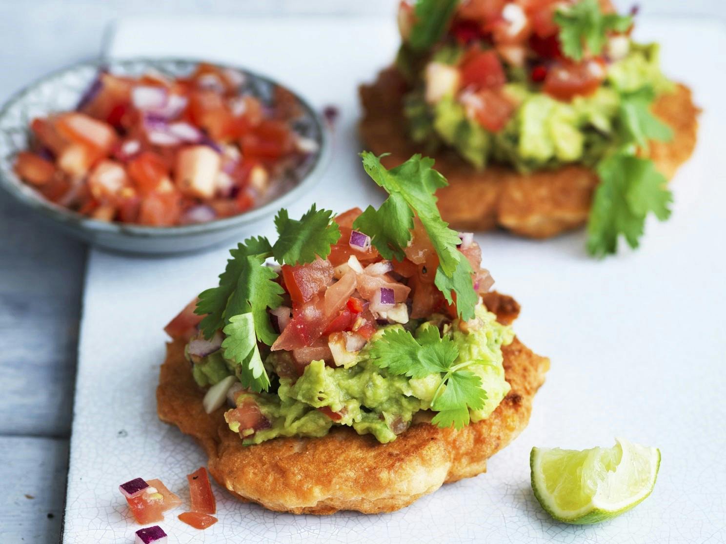 To laksebøffer med tomatsalsa og guacemole på et fad.