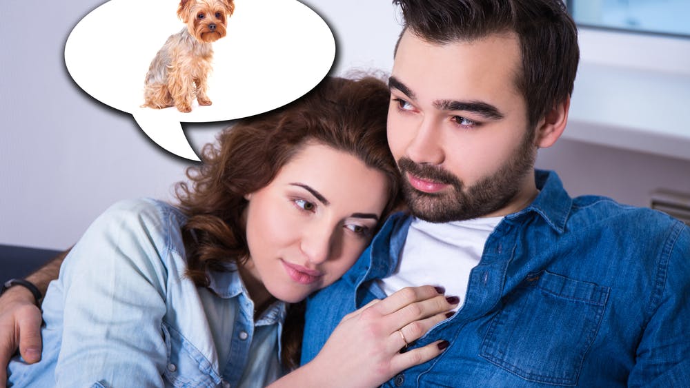 Kvinde og mand sidder sæt sammen i sofa, og kvinden tænker på sin hund.