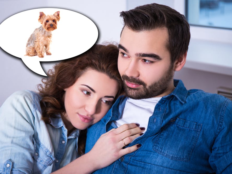 Kvinde og mand sidder sæt sammen i sofa, og kvinden tænker på sin hund.
