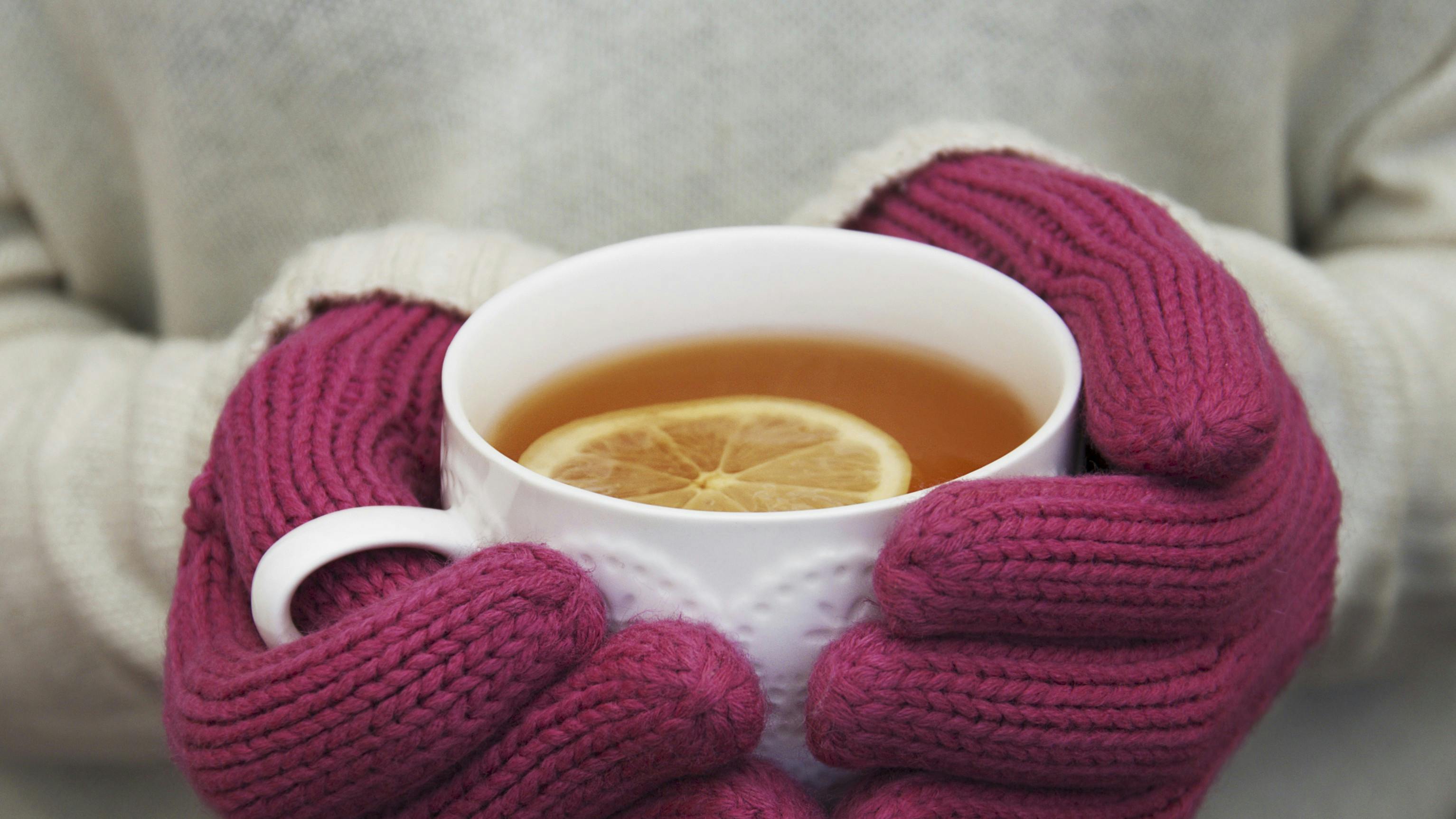 Kvinde med varme luffer holder en kop te