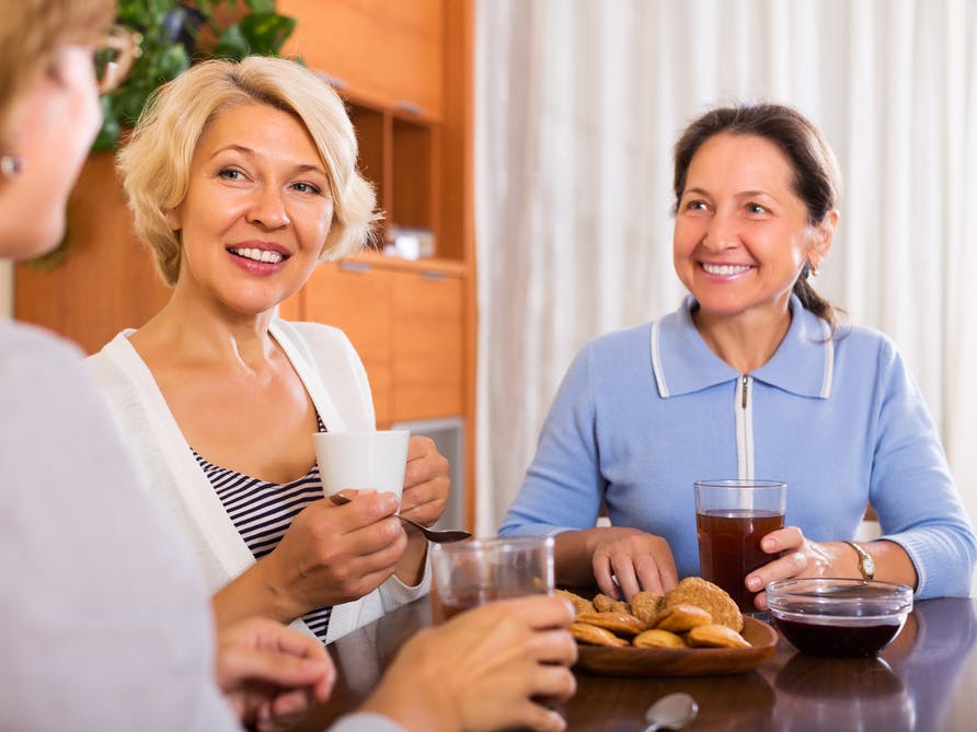 Tre kvinder sidder og taler sammen over en kop kaffe