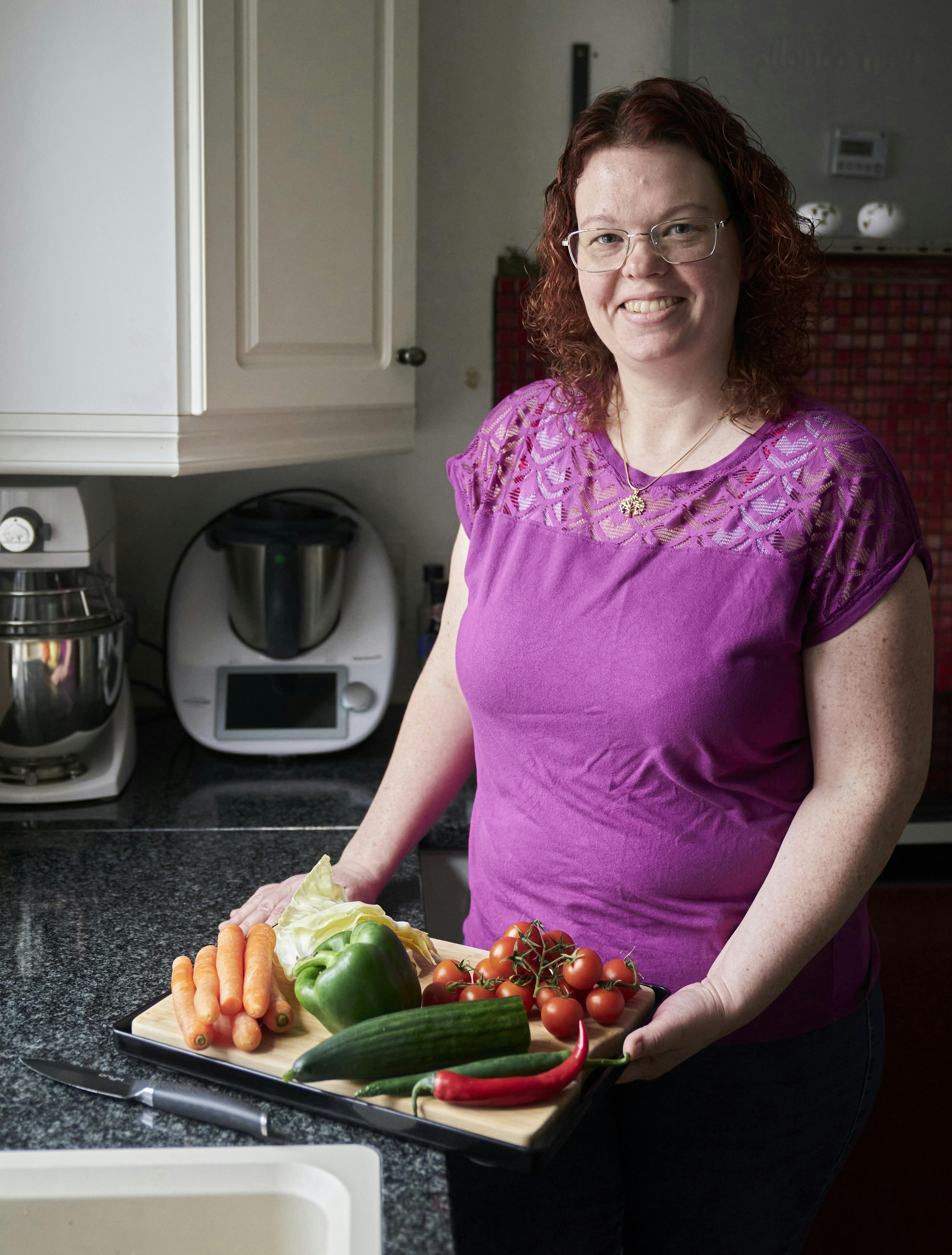 Michelle i sit køkken med et skærebræt fyldt med grøntsager.
