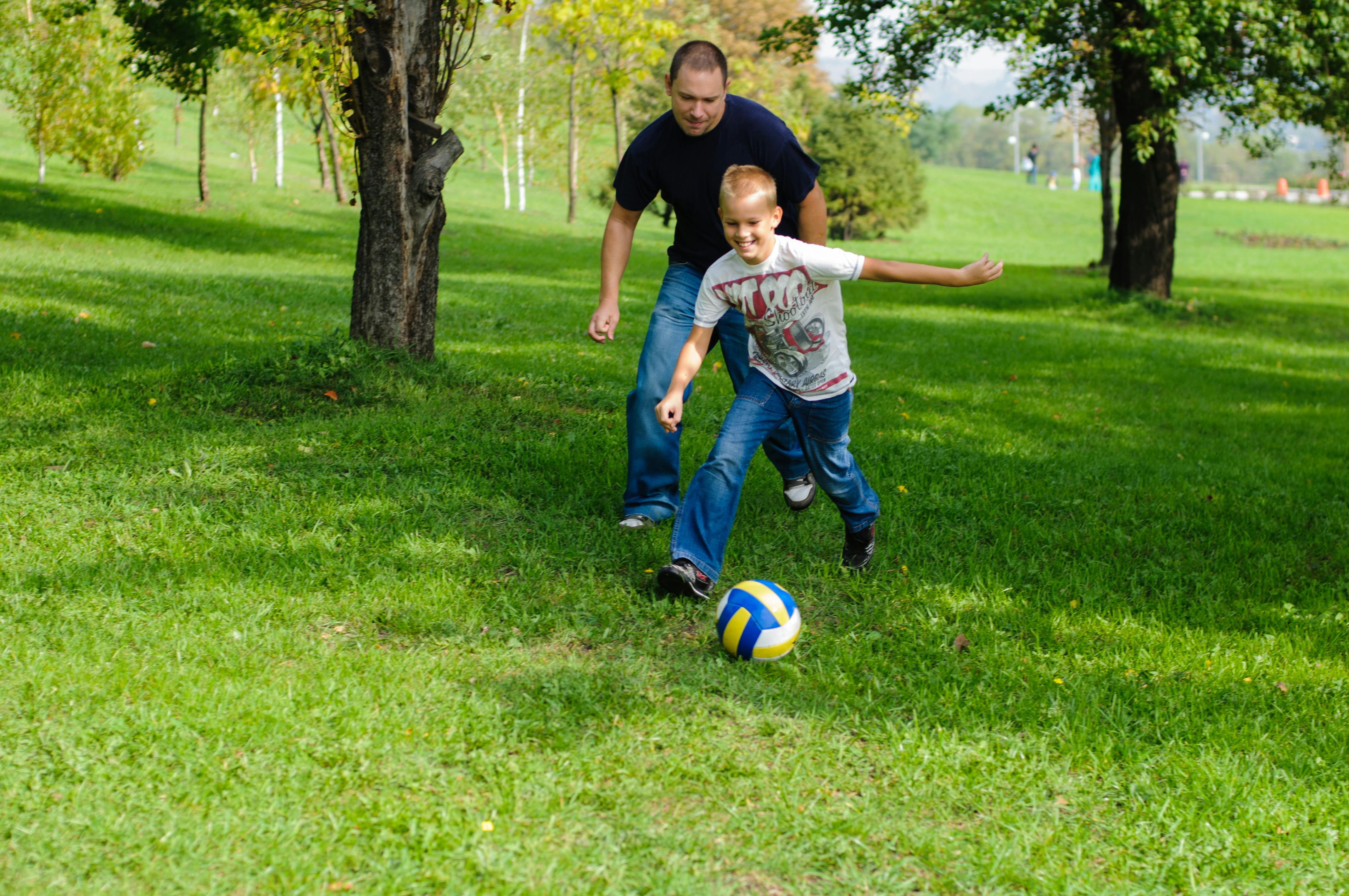 Far og søn spiller fodbold i haven.