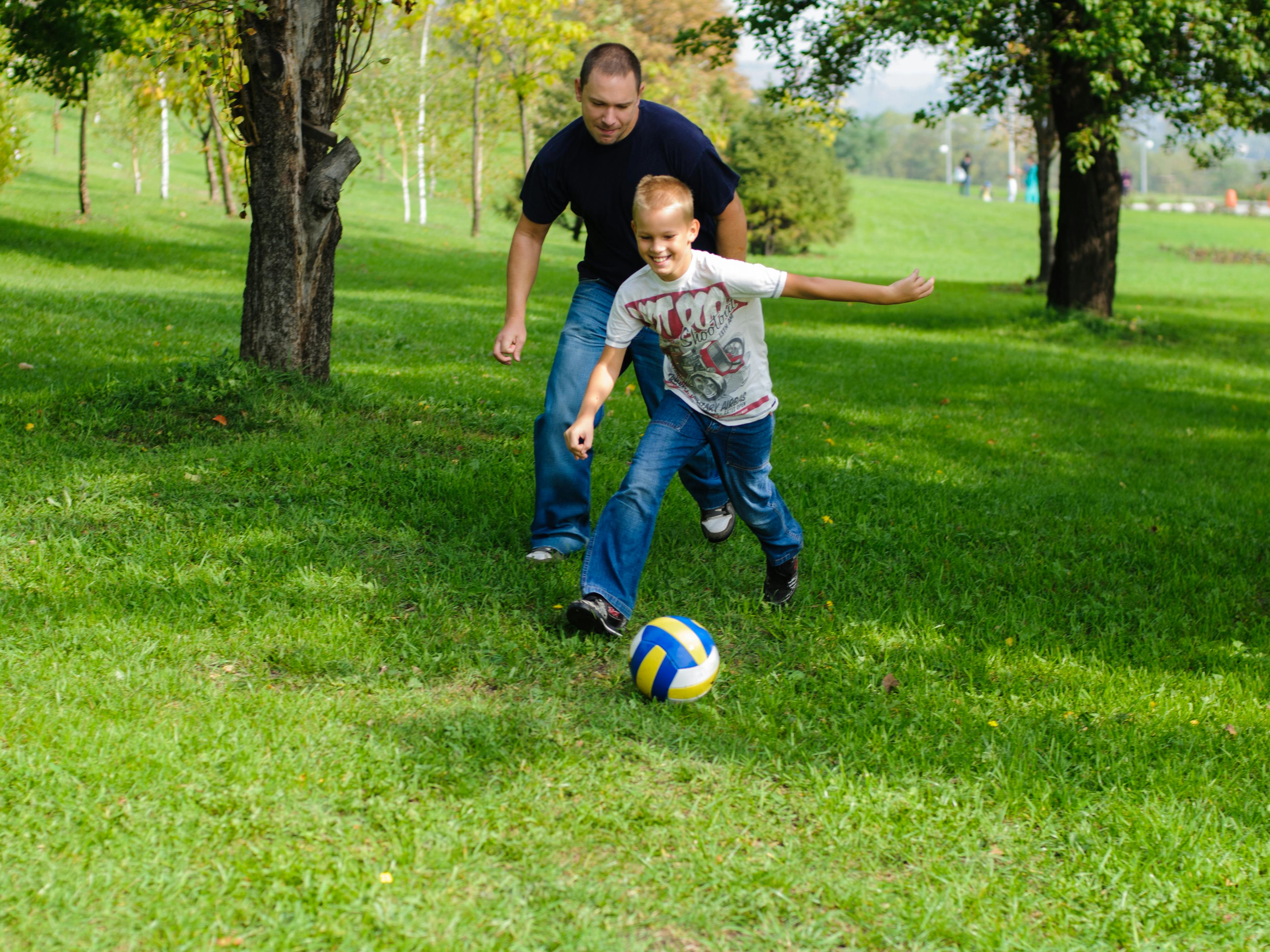 Far og søn spiller fodbold i haven.