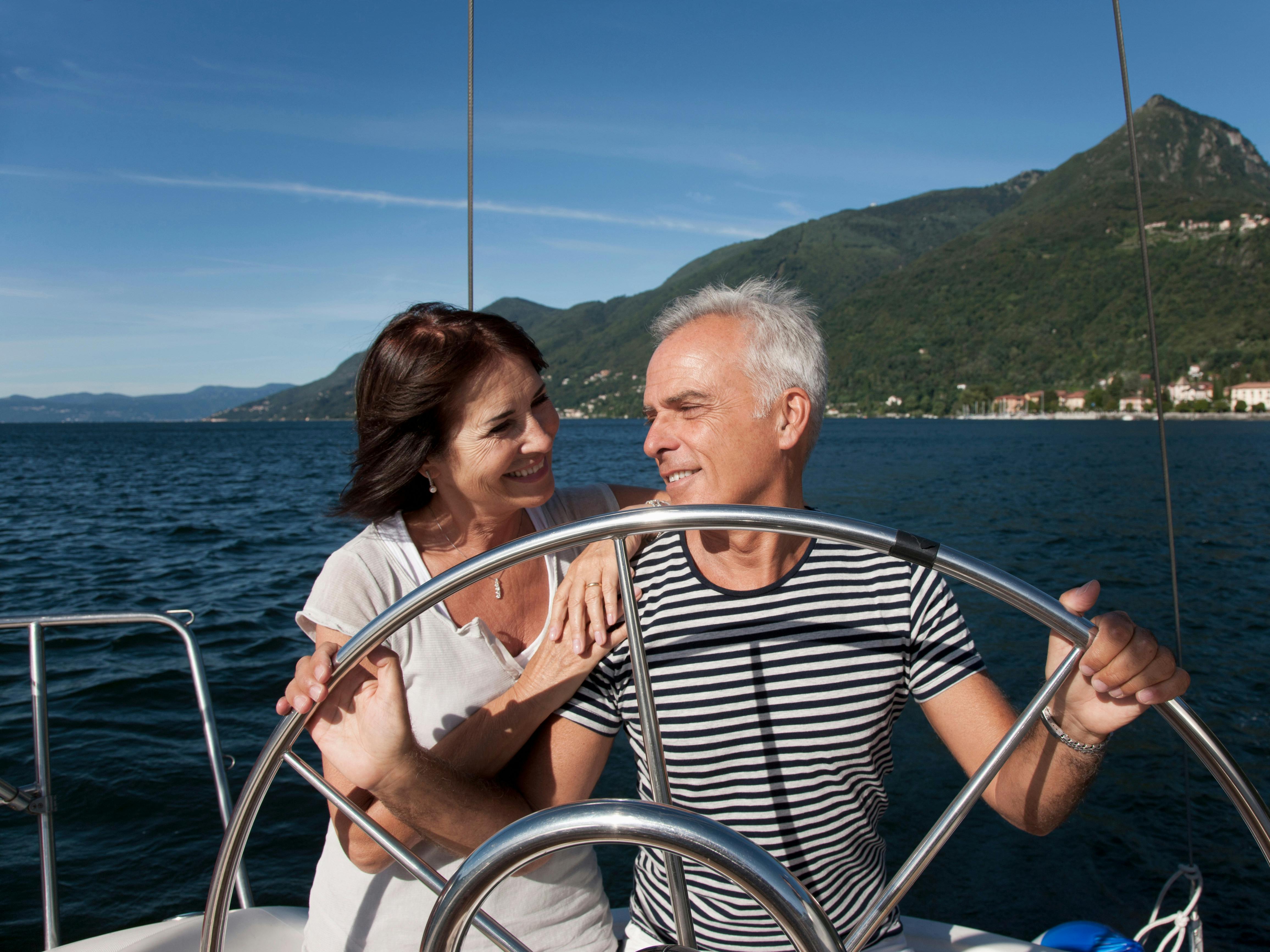 Midaldrende par står ved roret på deres båd