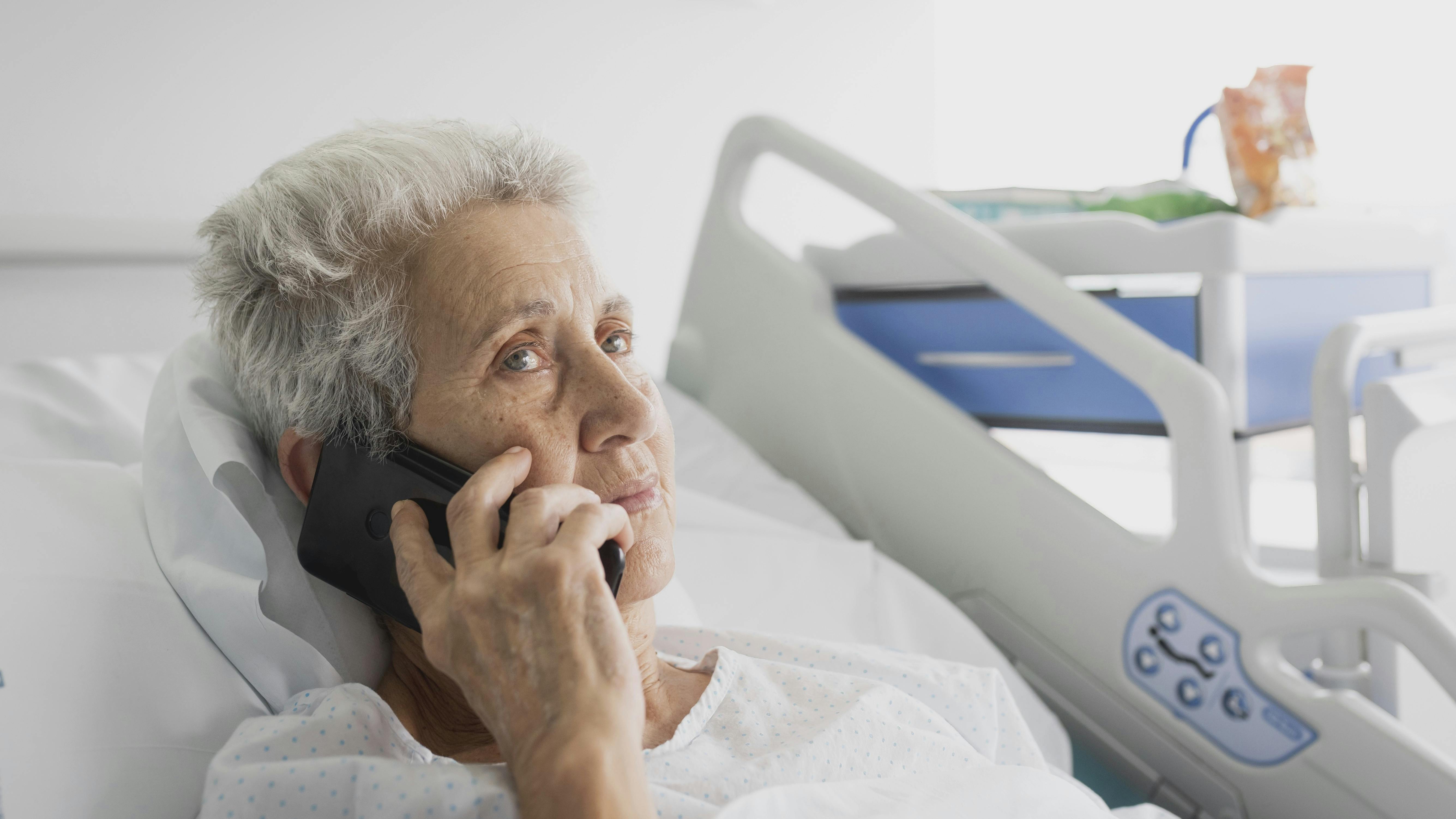 sick hospitalized elderly woman talking on the phone